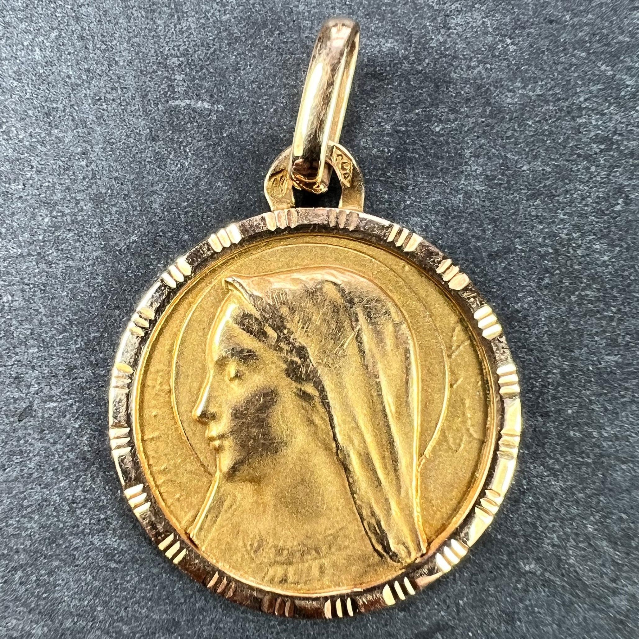 A French 18 karat (18K) yellow gold charm pendant designed as a medal depicting the Virgin Mary within a ridged and engraved frame. Stamped with the eagle's head mark for 18 karat gold and French manufacture and the maker's mark for
