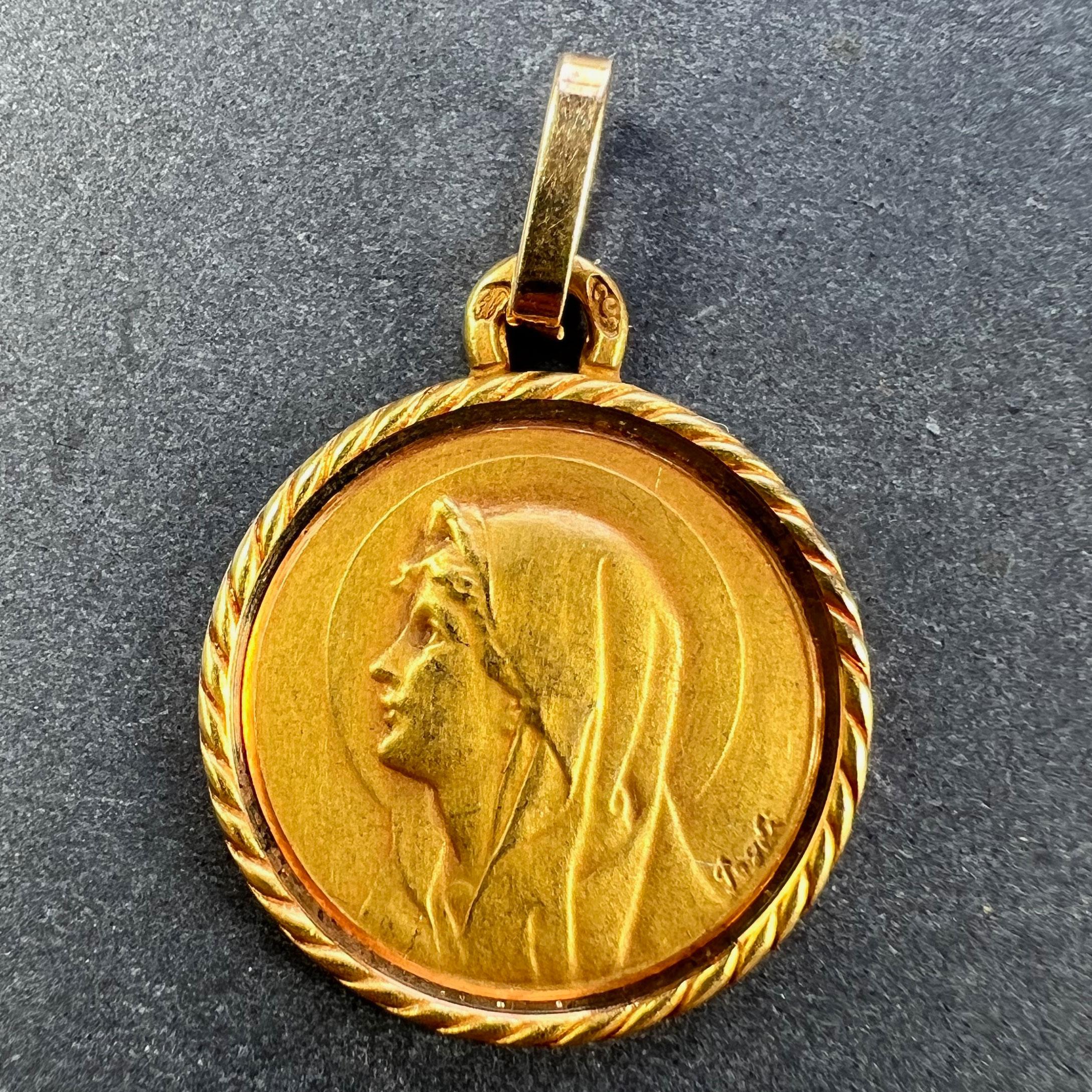 A French 18 karat (18K) yellow gold charm pendant designed as a medal depicting the Virgin Mary with a halo and a rope twist border. Signed Pagdi, stamped with the eagle mark for 18 karat gold and French manufacture with maker's mark for Perroud.