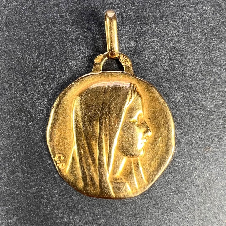 A French 18 karat (18K) yellow gold charm pendant designed as a medal depicting the Virgin Mary signed CP.  Stamped with the eagle’s head mark for 18 karat gold and French manufacture, and maker’s mark for Perroud.

Dimensions: 2 x 1.7 x 0.1 cm (not