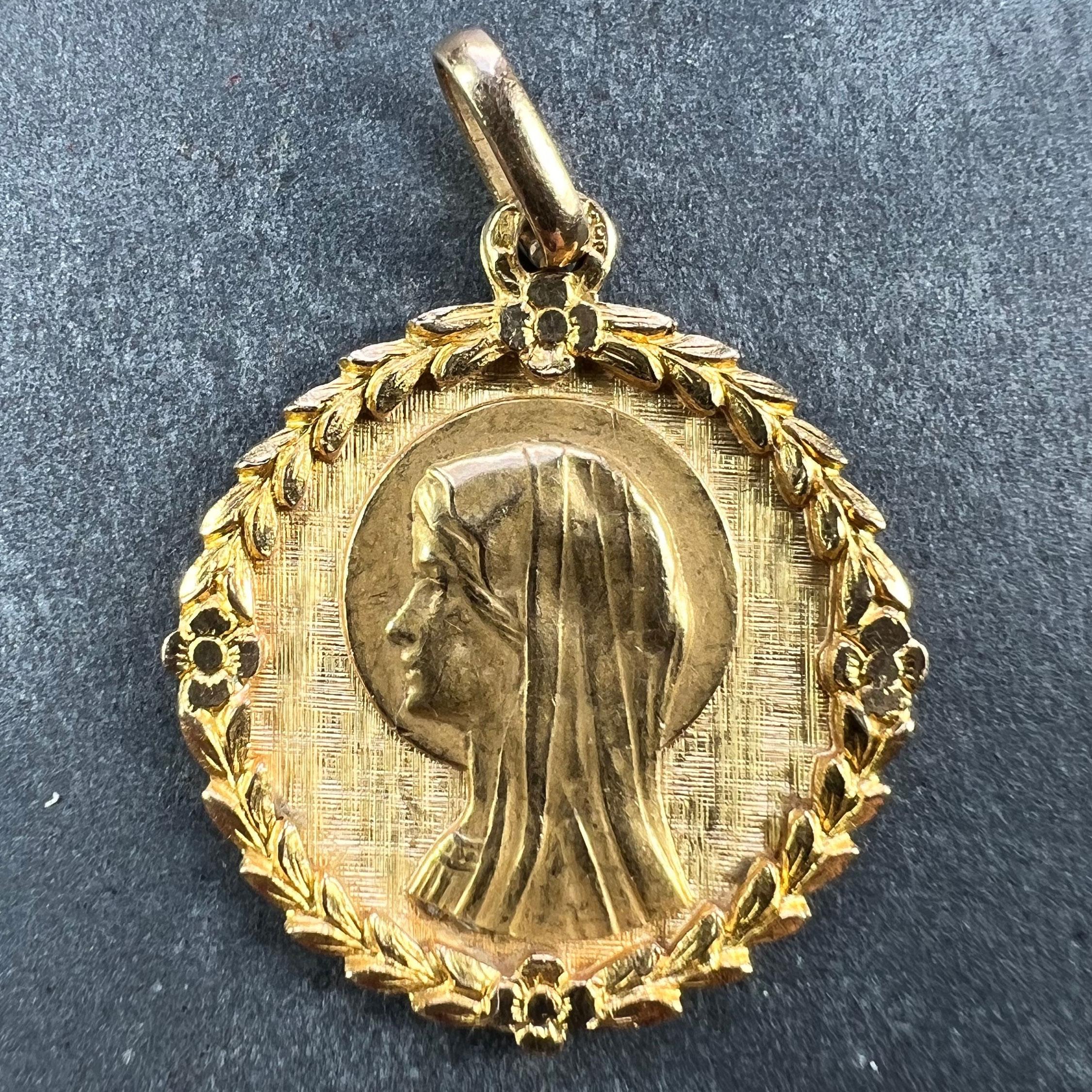 Ein französischer Anhänger aus 18 Karat (18K) Gelbgold in Form einer runden Medaille, die die Jungfrau Maria in einem gravierten Rahmen aus Blättern und Blumen darstellt. Gestempelt mit dem Adlerkopf für französische Herstellung und 18-karätigem