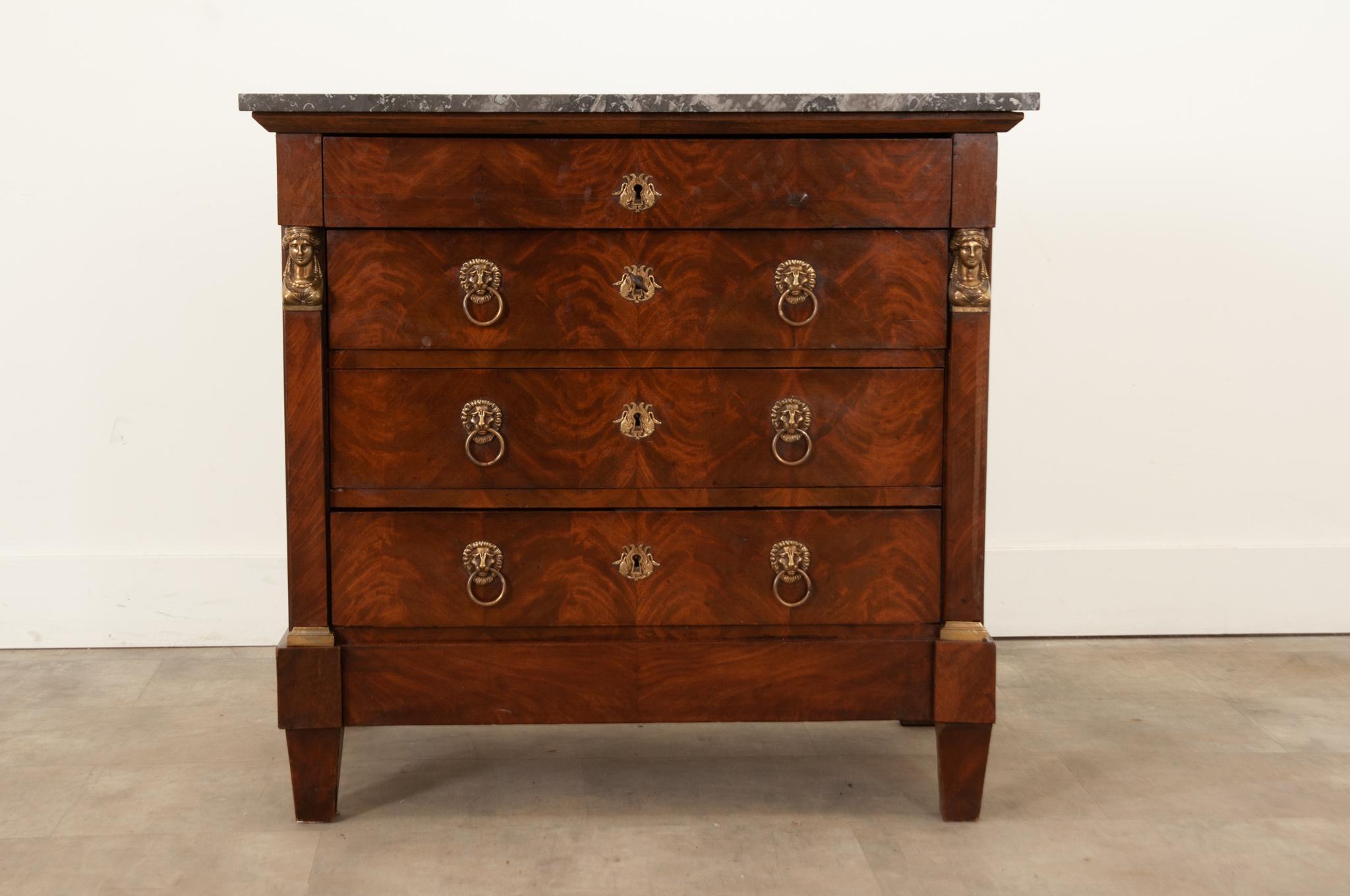 Four drawers and neoclassical details compose this outstanding Empirical commode hand-crafted in France circa 1810. This case piece is topped with an interesting piece of black, gray and white fossil marble that, along with the body, has patinated