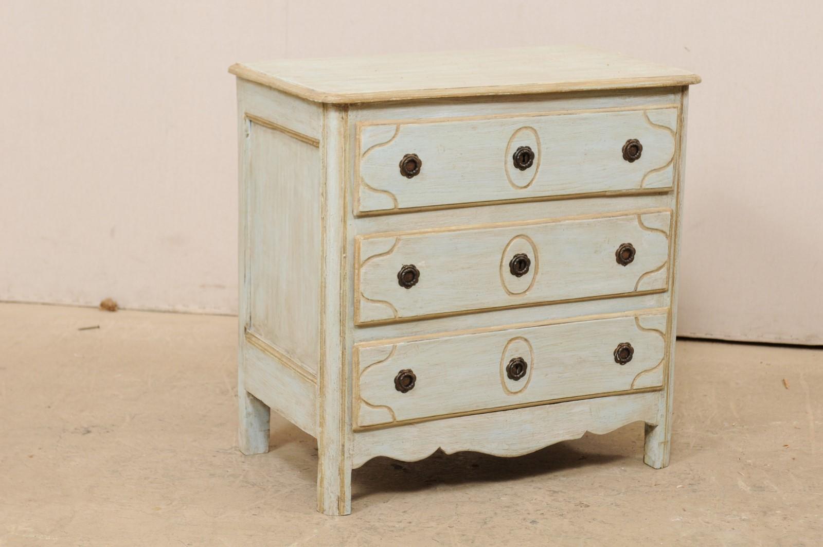 A French small-sized chest of drawers from the turn of the 18th and 19th century. This sweet antique chest from France features a slightly overhanging and rectangular-shaped top, above a case which houses three decoratively carved drawers. The top