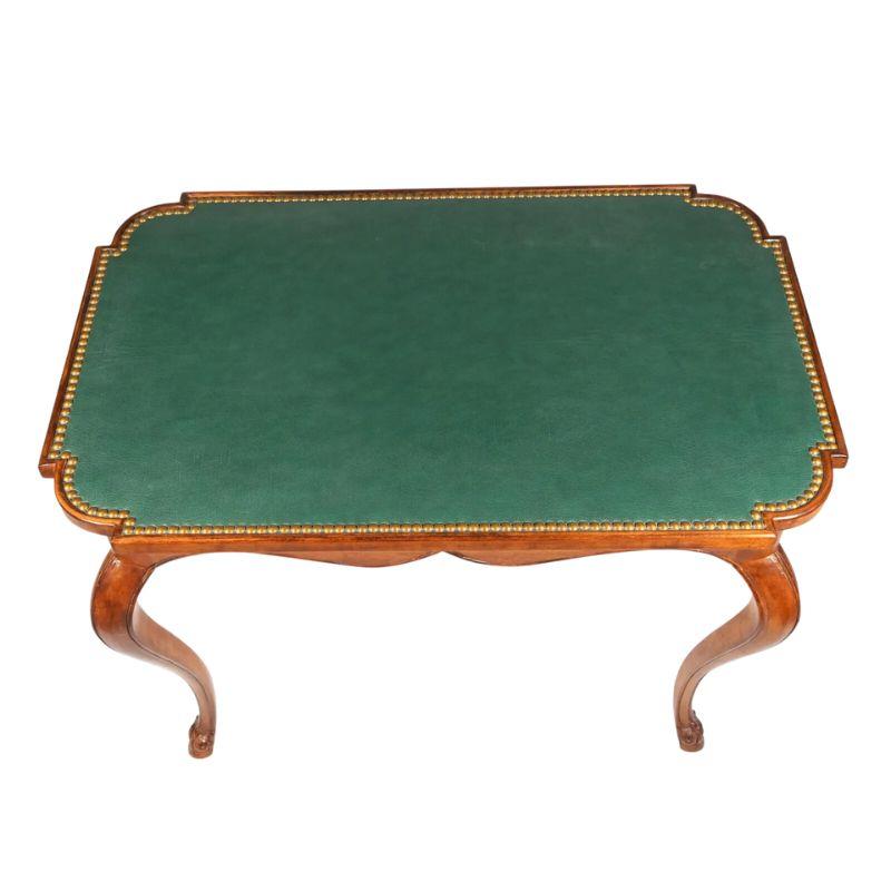 A French style petite table with green leather top, nail head trim and a quatrefoil cut at each table corner.  The table has lovely cabriole legs, slender claw foot feet and a shaped apron.  An elegant table can be used as a writing desk or accent