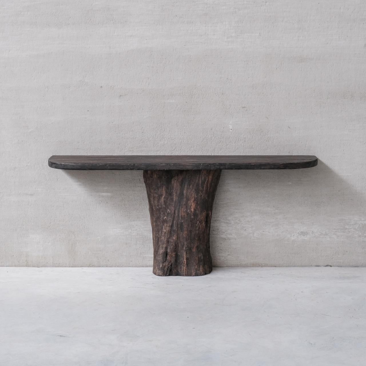 A primitive style console table. 

France, c1970s. 

A marriage of petrified wooden base and a later ebonised top. 

We have added fixings to make the top fit in seamlessly. 

A wall based unit ideal for a hall way, under a tv etc. 

Good