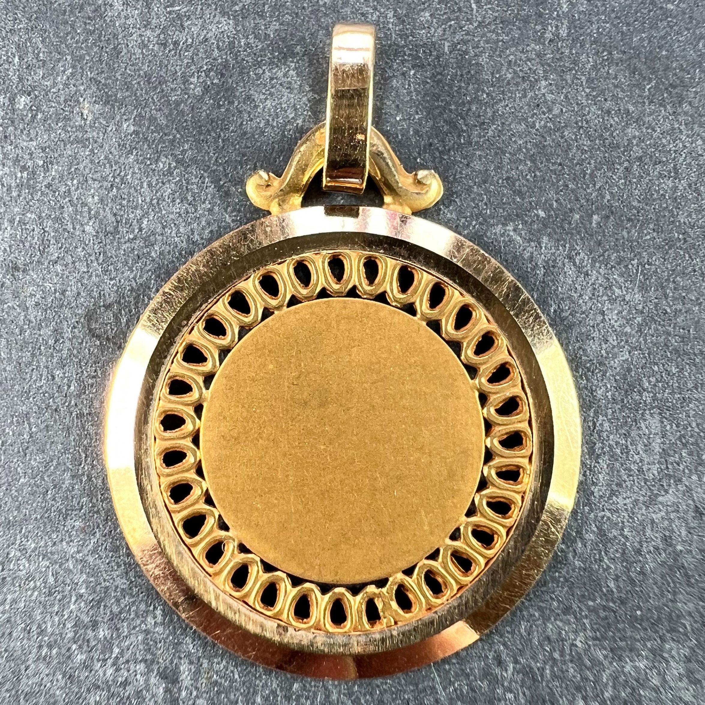Pendentif à breloques français en or jaune 18 carats (18K) conçu comme une médaille ronde avec un bord percé et un entourage poli et strié. Estampillé de la tête d'aigle de fabrication française et de l'or 18 carats, ainsi que d'une marque de