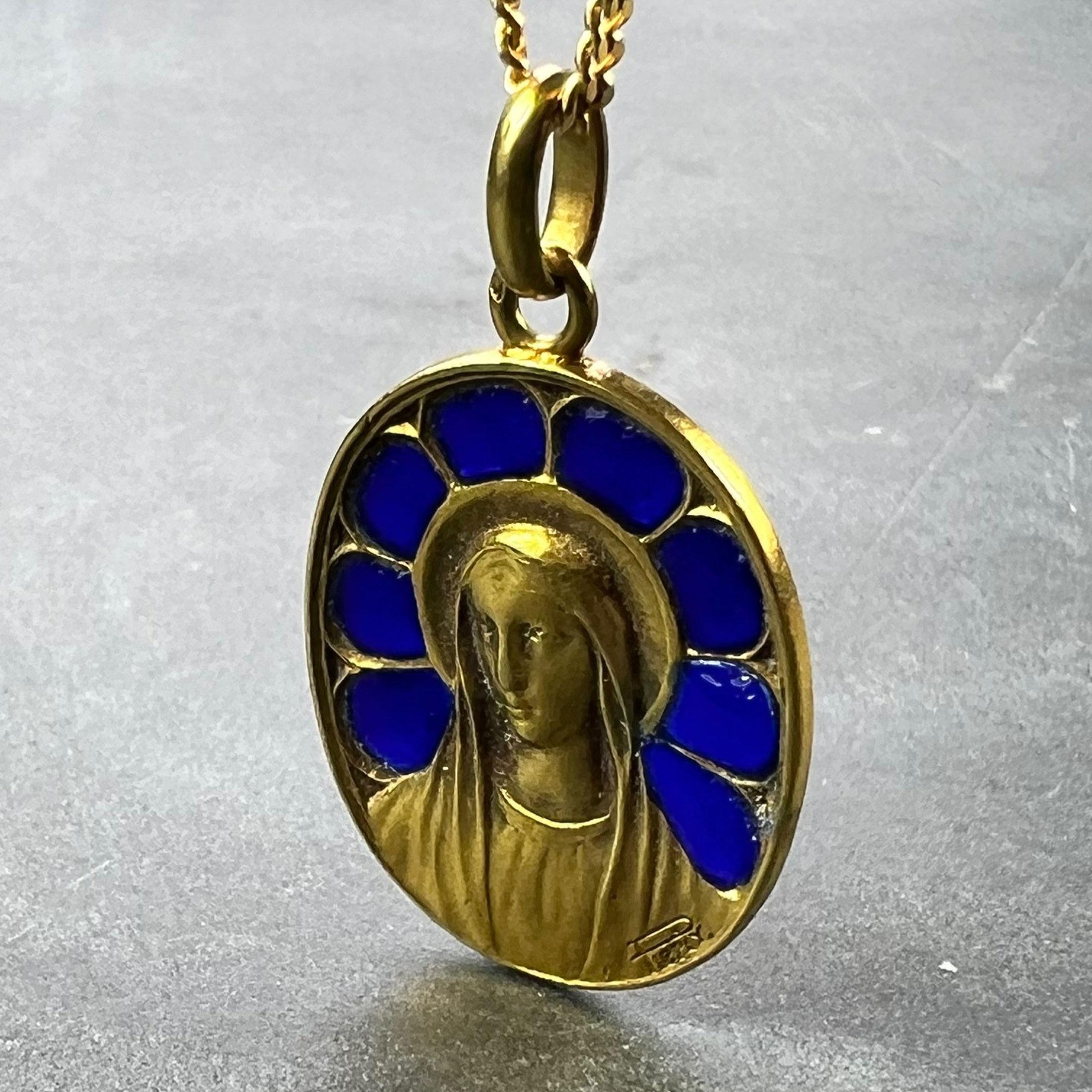 A French 18 karat (18K) yellow gold charm pendant designed as an oval medal depicting the Virgin Mary with plique a jour blue enamel surround in a gothic arch stained window effect. Signed Pierly, stamped with the eagle's head for 18 karat gold and