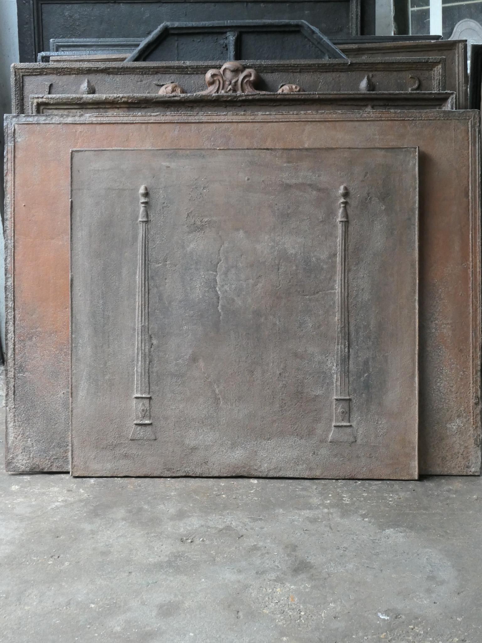 18th - 19th century French neoclassical fireback with two pillars of freedom. The pillars symbolize the value liberty, one of the three values of the French revolution. 

The fireback is made of cast iron and has a natural brown patina. Upon