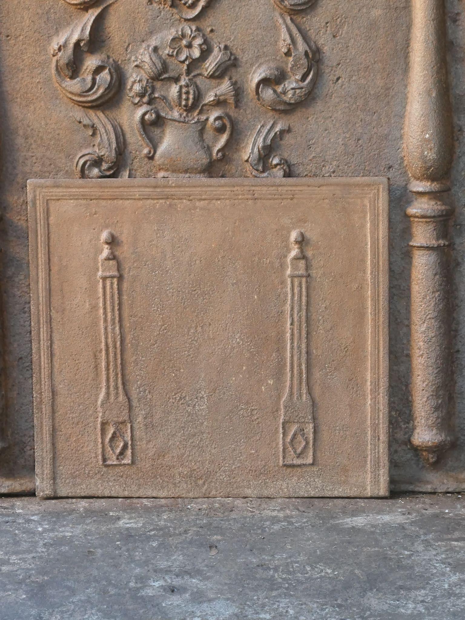 Early 19th century French neoclassical fireback with two pillars of freedom. The pillars symbolize the value liberty, one of the three values of the French revolution. 

The fireback is made of cast iron and has a natural brown patina. Upon request,