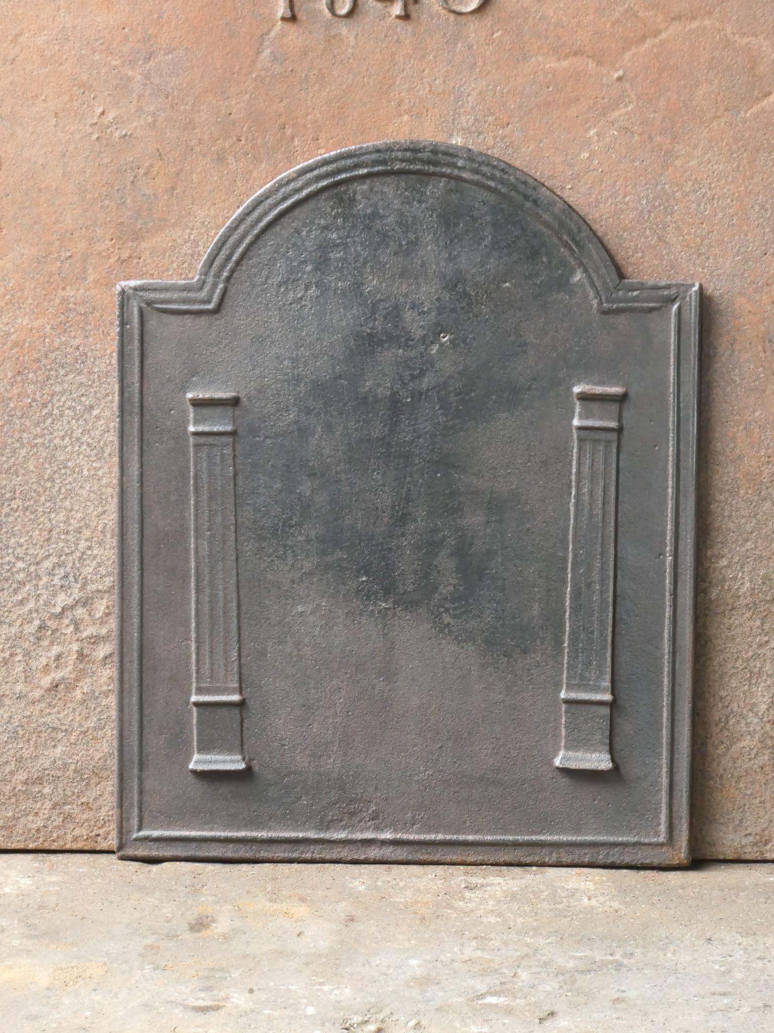 19th century French Neoclassical Period fireback with two pillars of freedom. The pillars symbolize the value liberty, one of the three values of the French revolution. 

The fireback is made of cast iron and has a natural brown patina. Upon