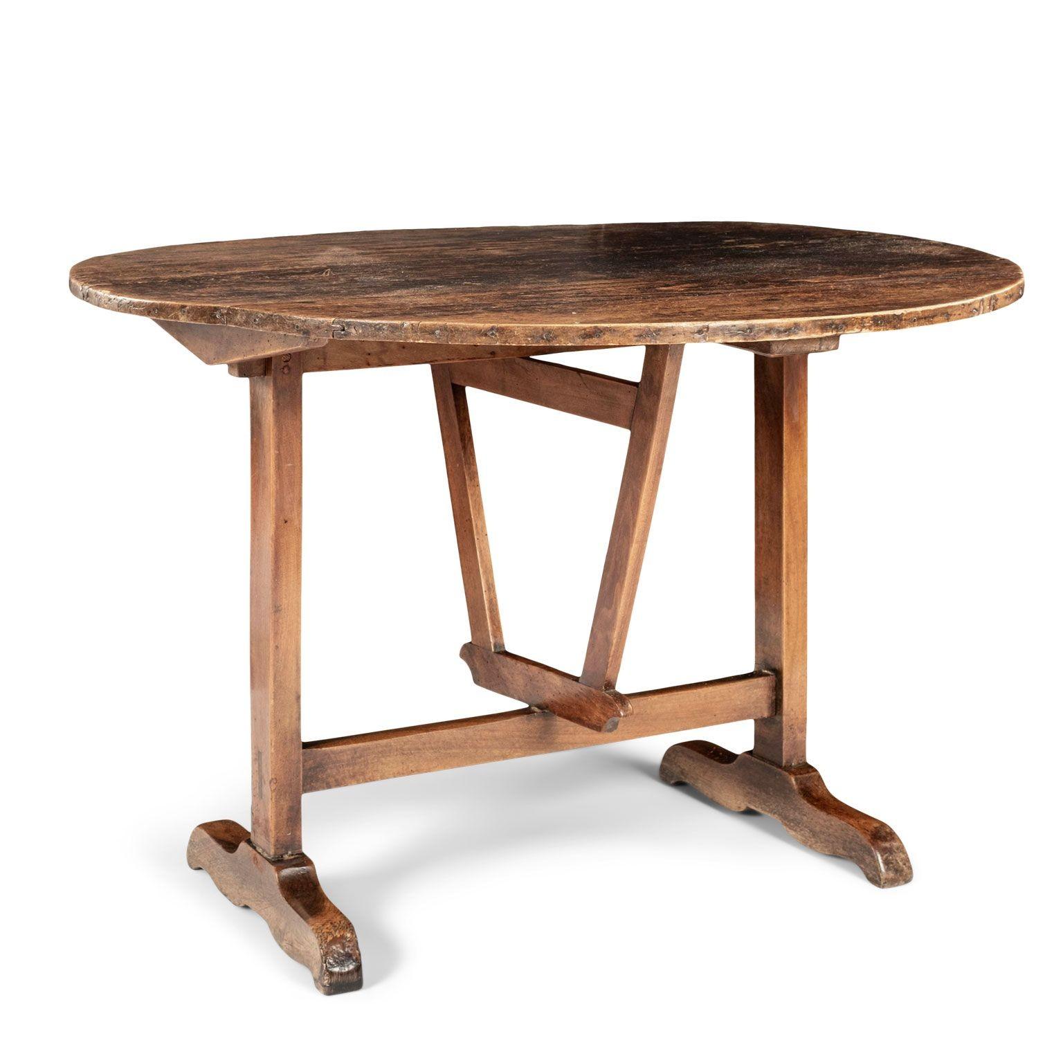 French pine and fruitwood wine tasting table, or vendange table, dating to the late 19th century. Circular pine top upon a hinged fruitwood harp-support. Finish is beautifully irregular dark-to-light brown and partially sun-bleached in places.