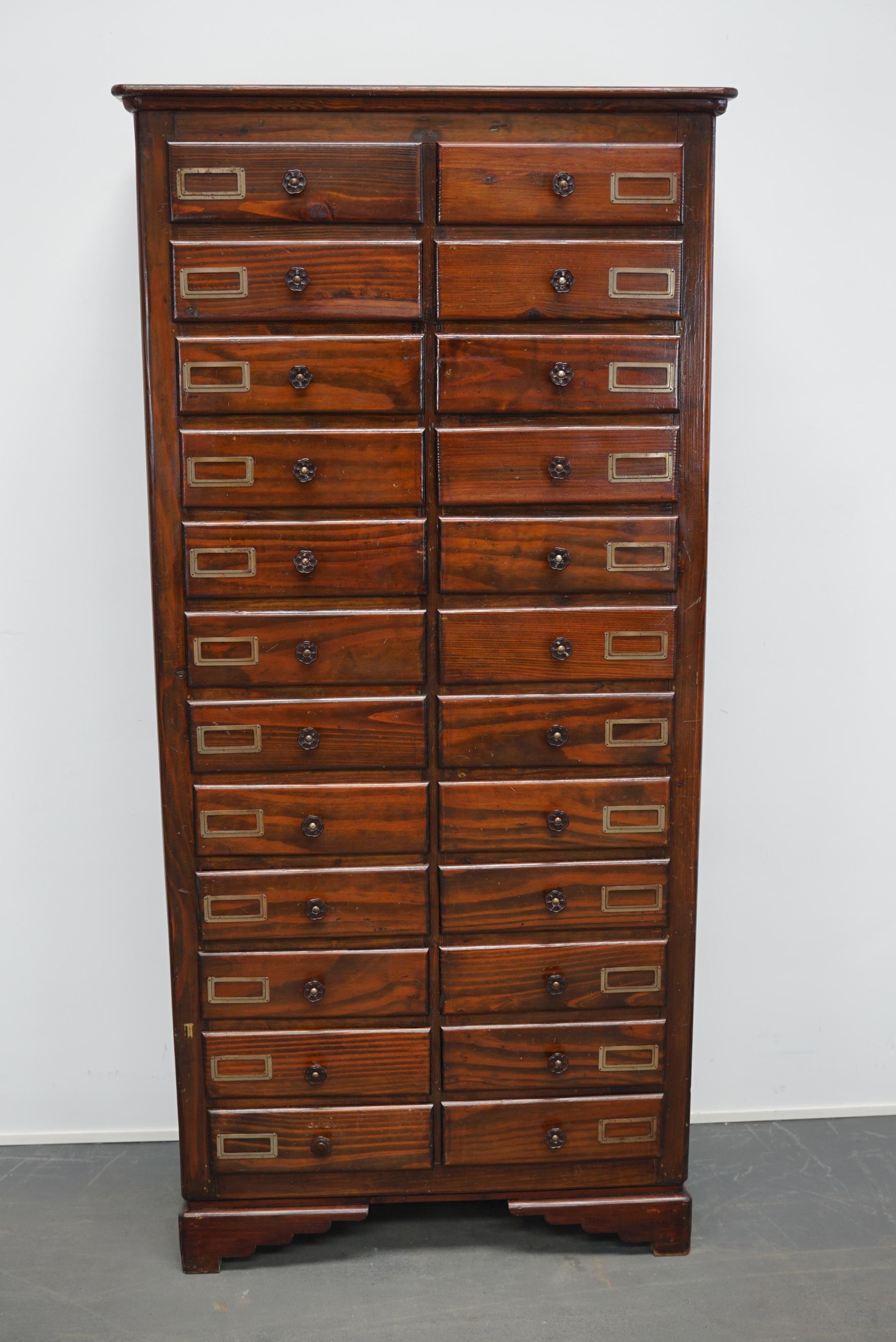 This apothecary cabinet of drawers was designed, circa 1950s in France. The piece is made from pine and features 24 drawers with bakelite hardware. The interior dimensions of the drawers are: D 37 x W 29 x H 8.5 cm. 
 