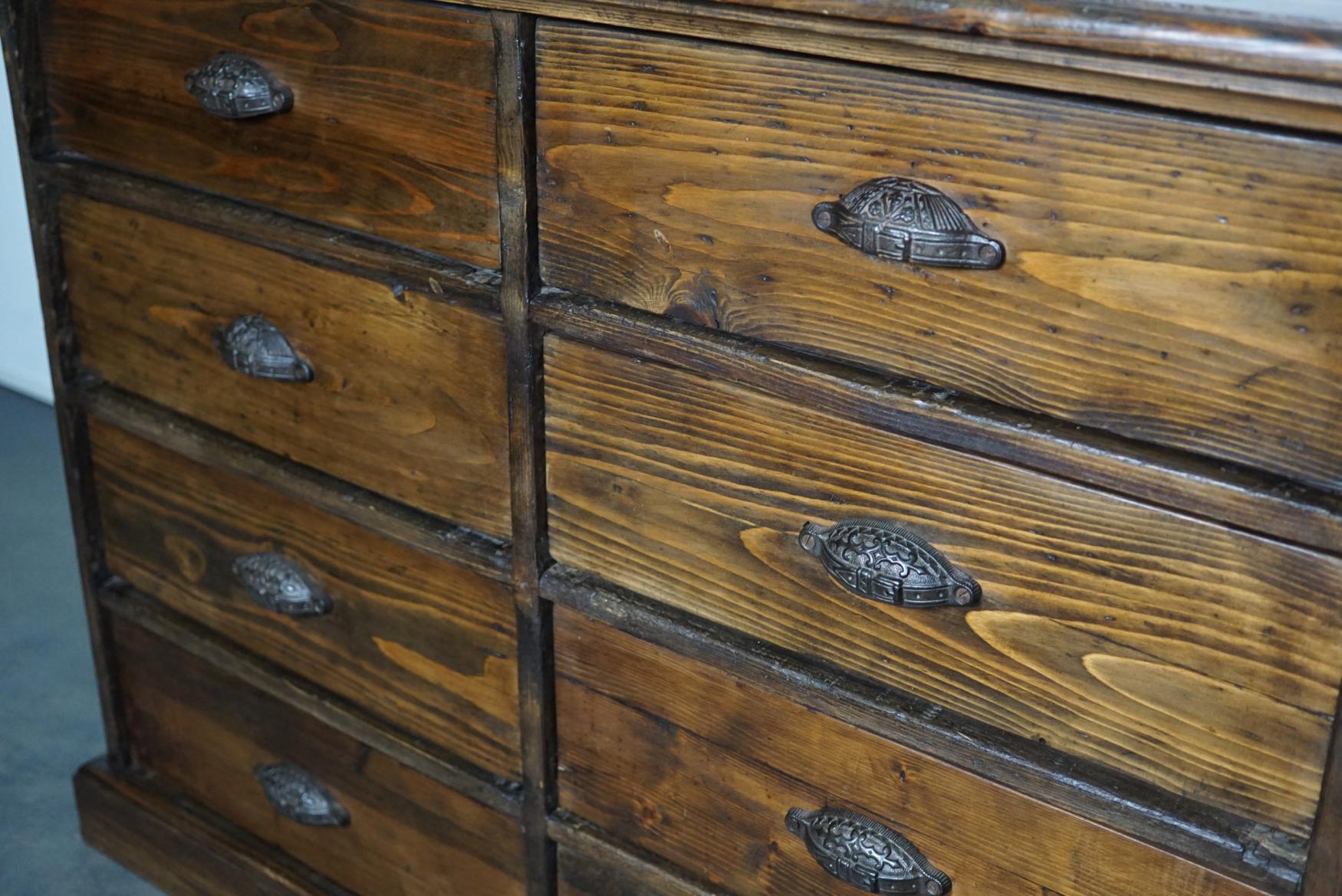 This stunning pine apothecary cabinet was made circa 1890s in France. It features 8 large drawers with ornate cast iron cup handles. It was used as a small shop counter in its early life.