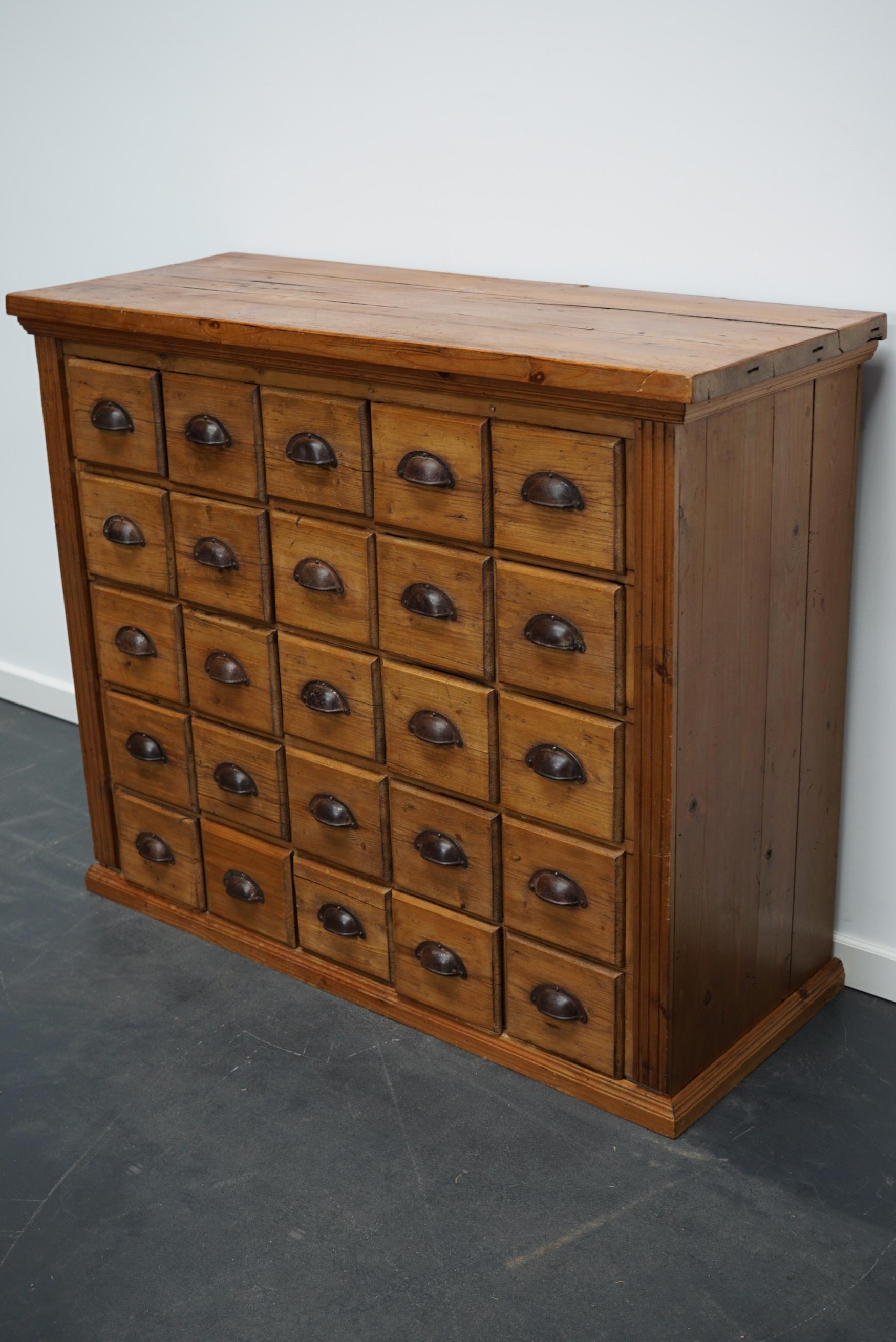 This apothecary cabinet was made circa mid 20th century in France. The piece is made from pine and features 25 drawers with metal cup handles. The interior dimensions of the drawers are: DWH 33 x 13 x 12 cm.