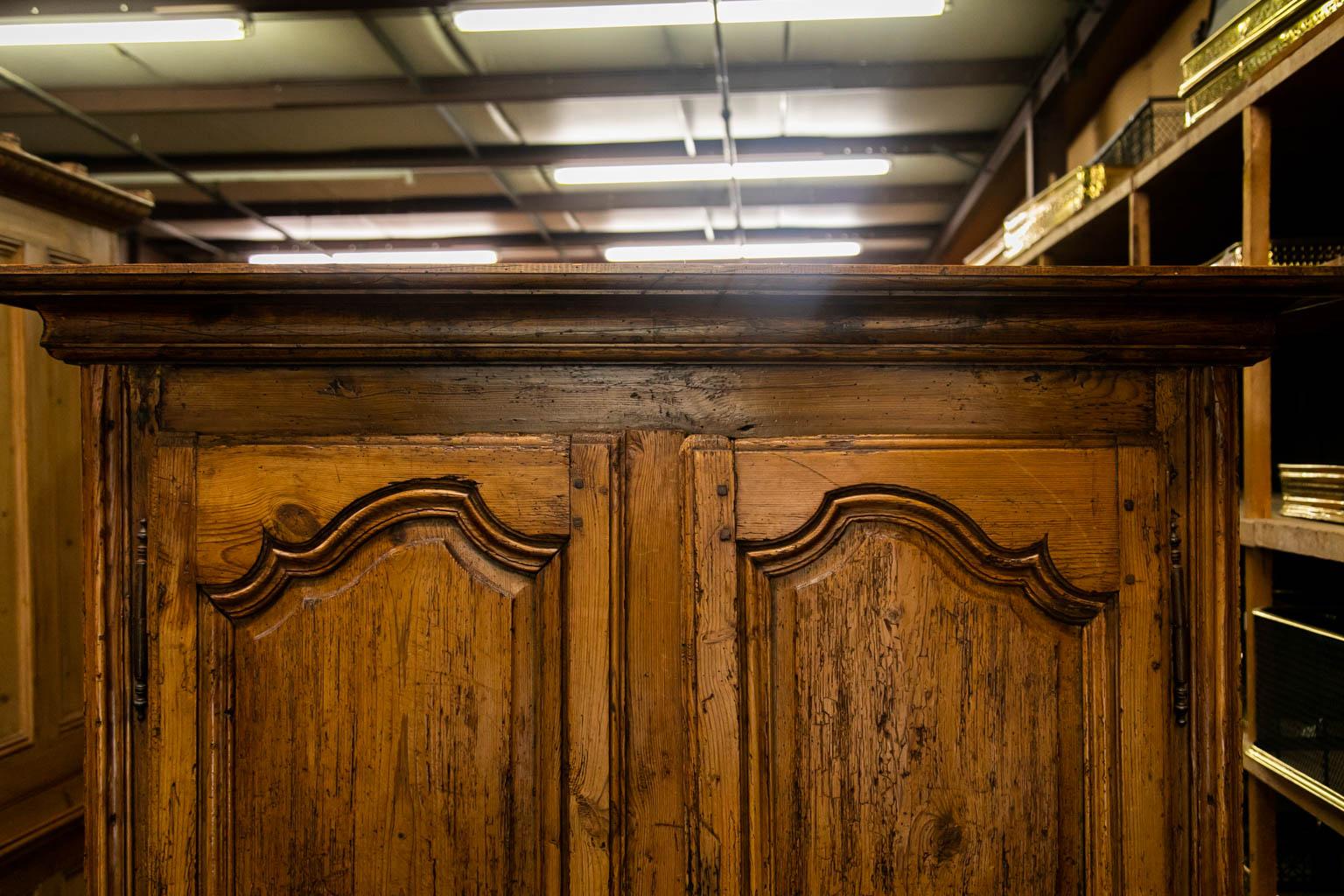 This armoire has exposed double pegged construction. The hinges are original and escutcheons are later. Each door has shaped raised panels framed with carved molding. The feet are later replacements. The sides have two recessed panels. The front