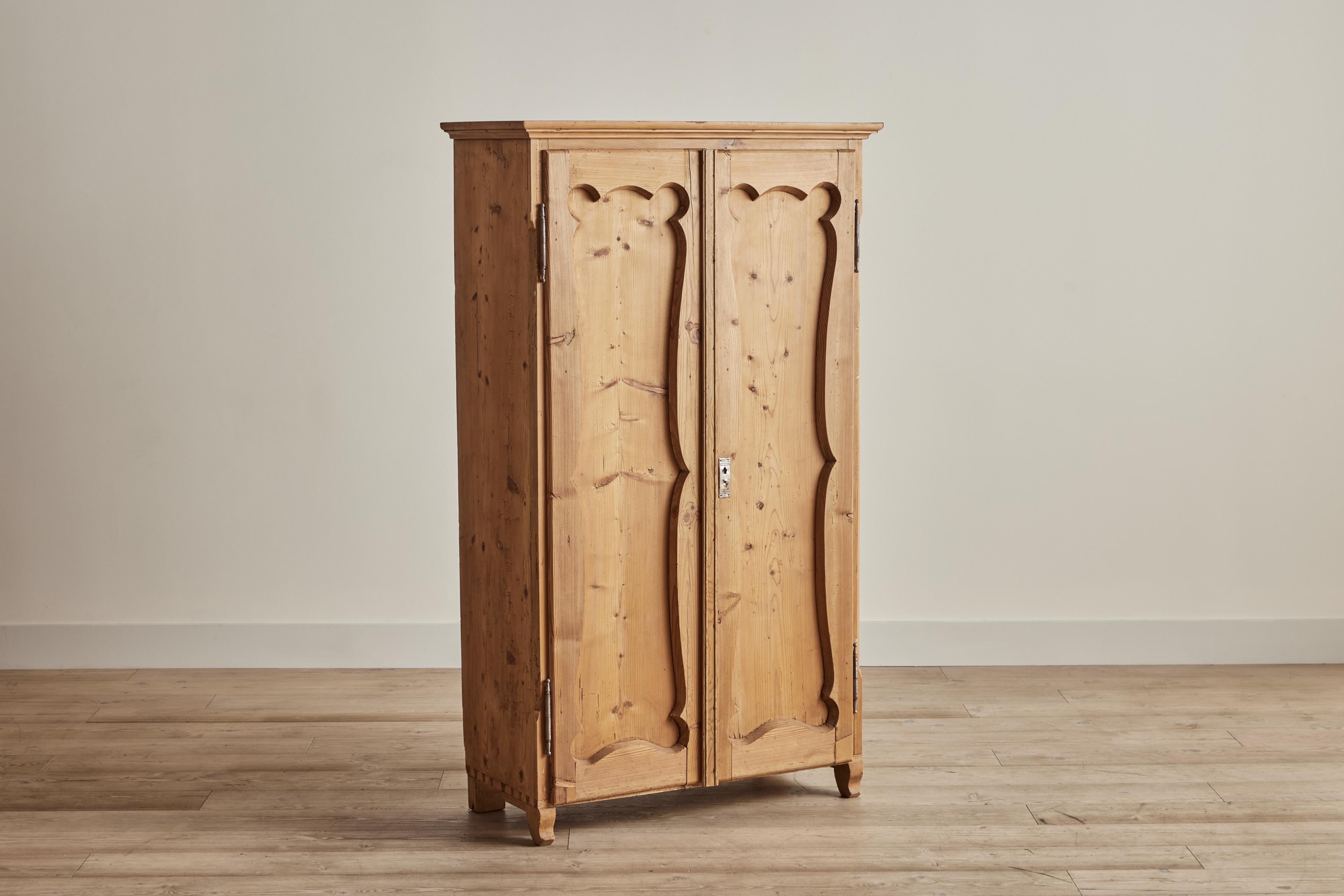 Nineteenth century pine wood armoire from France. This armoire has a petite footprint for clothing storage including a clothing rack inside and removable shelving. Cabinet comes with one key. Visible wear on wood is consistent with age and use.