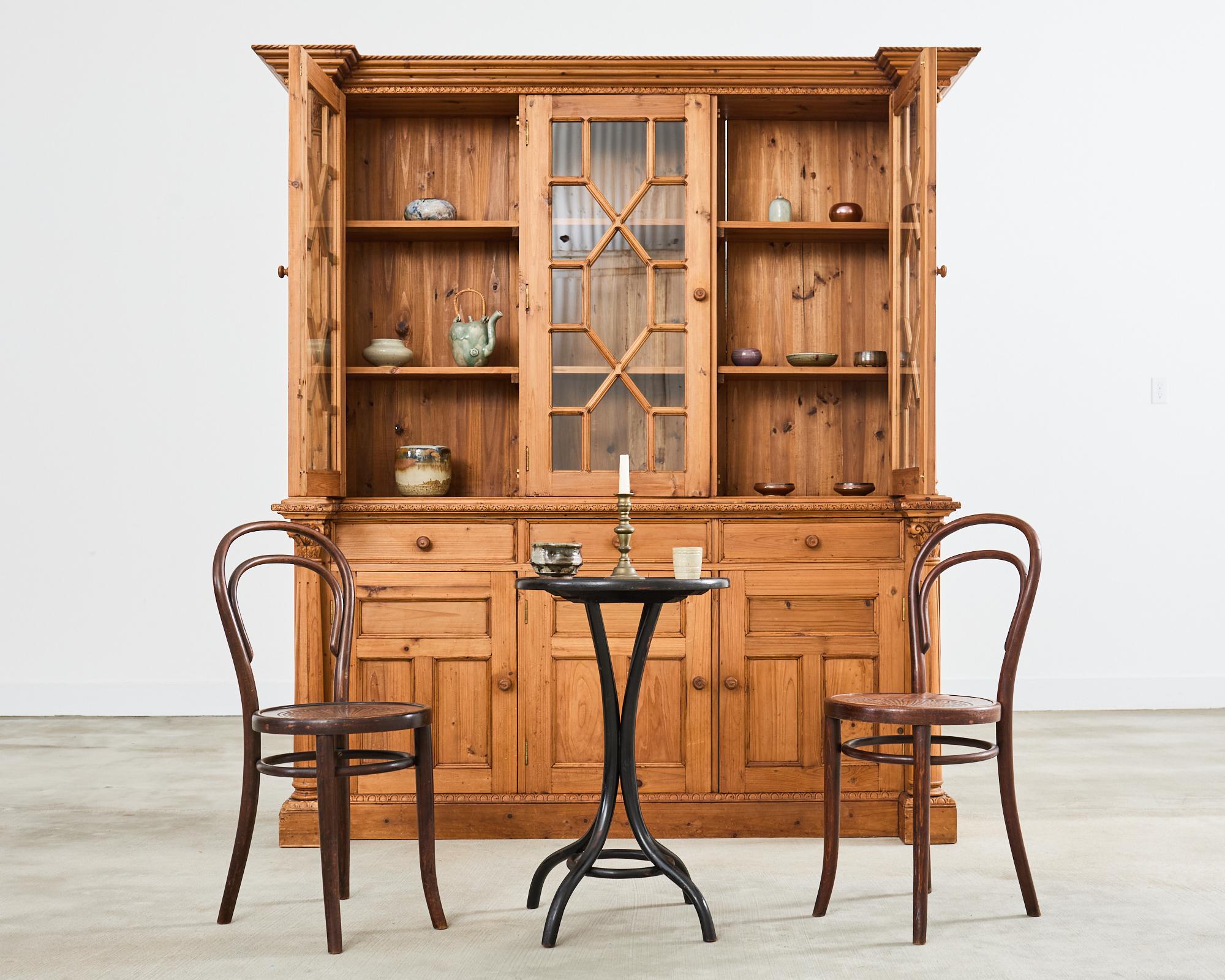 Incredibile mobile libreria in pino francese dell'inizio del XX secolo, con ante vetrate astrali e supporti a colonna corinzia in stile neoclassico su ogni lato. La cassa in due parti è sormontata da una cornice a gradini sostenuta da due colonne.