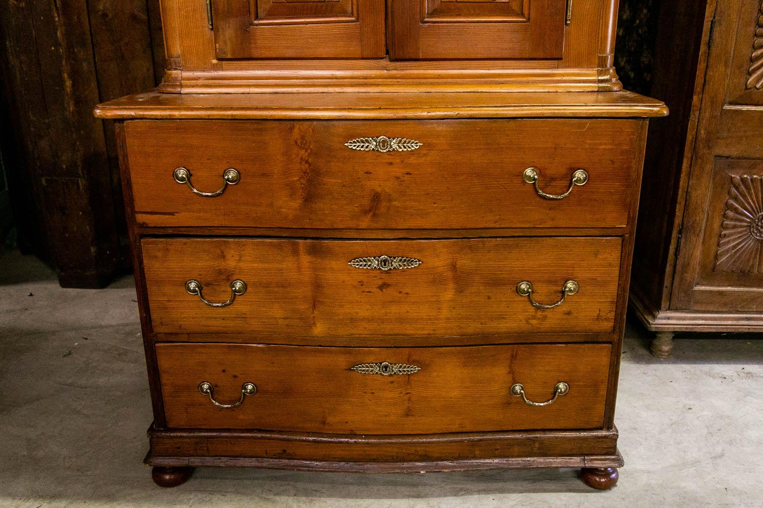 The upper doors of this buffet have carved shaped raised panels. The interior has two fixed shelves. The lower section has a serpentine shape. There are carved geometric raised panels on the sides. The top section has carved raised panels and solid