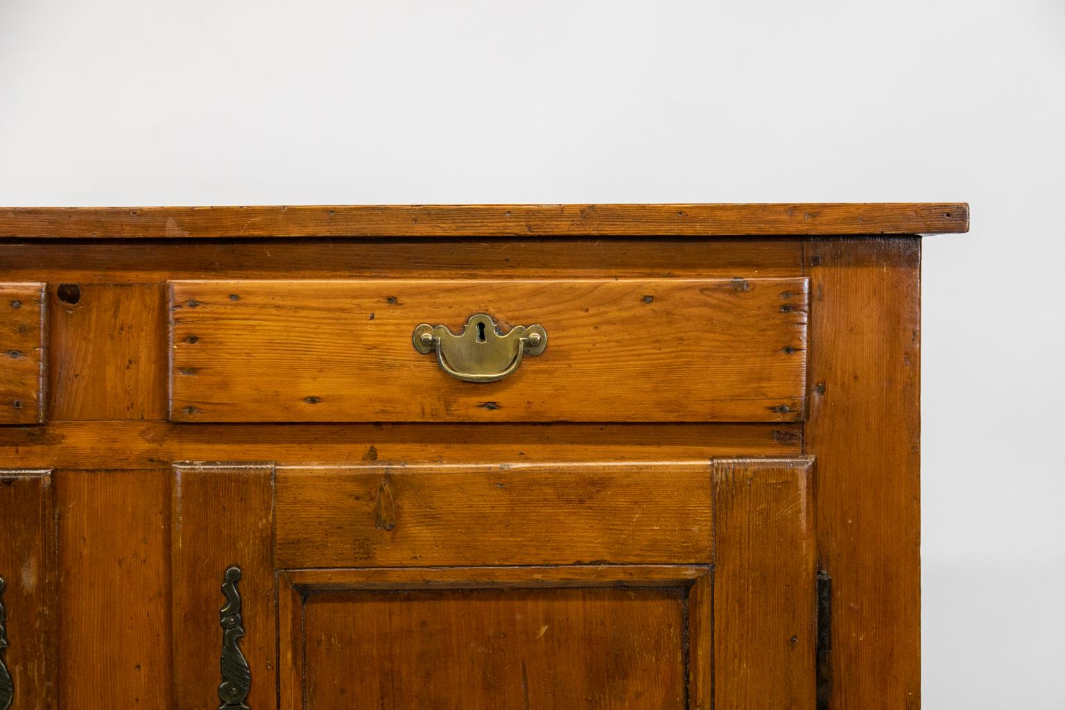 French pine buffet, with two drawers over two doors, the doors have recessed panels framed by beveled molding, the sides are both pine and oak. The steel hinges are original, but the brass hardware is later.