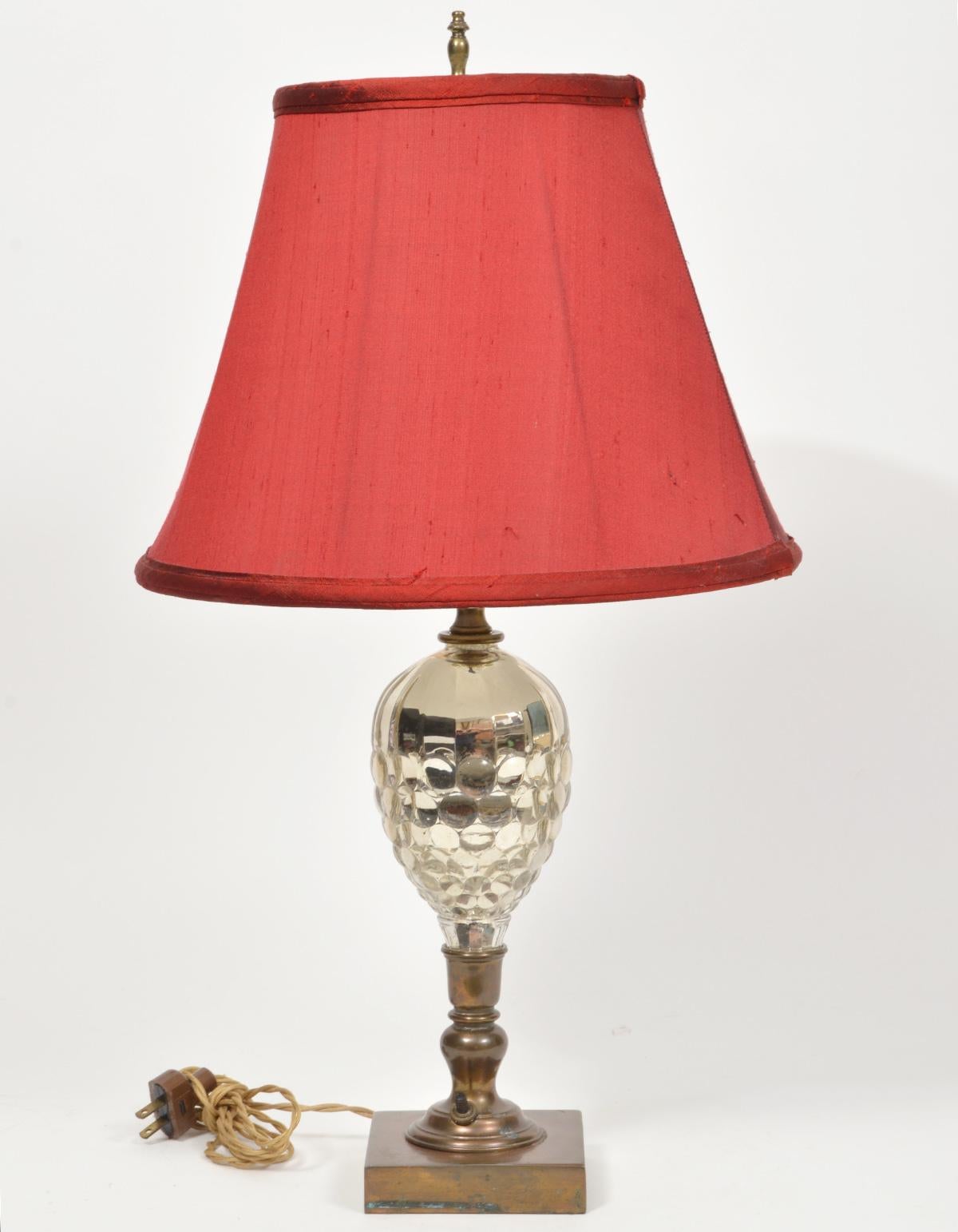 Mounted on patinated bronze bases and stems the pine cone shaped cut mercury glass gracefully reflect the light. These French table lamps likely date to the first half of the 20th century and come with the red shades shown.