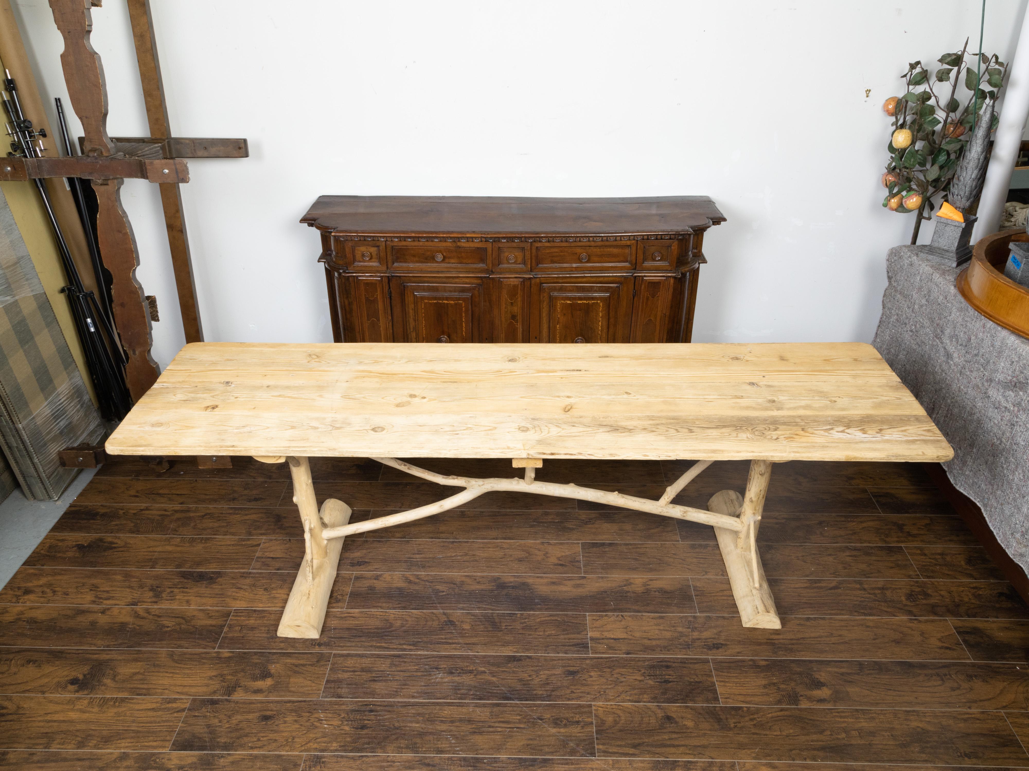 A French pine farm table from the mid 20th century, with twig trestle base. Created in France during the midcentury period, this farm table features a rectangular planked pine top sitting above an unusual twig trestle base. Boasting a nicely