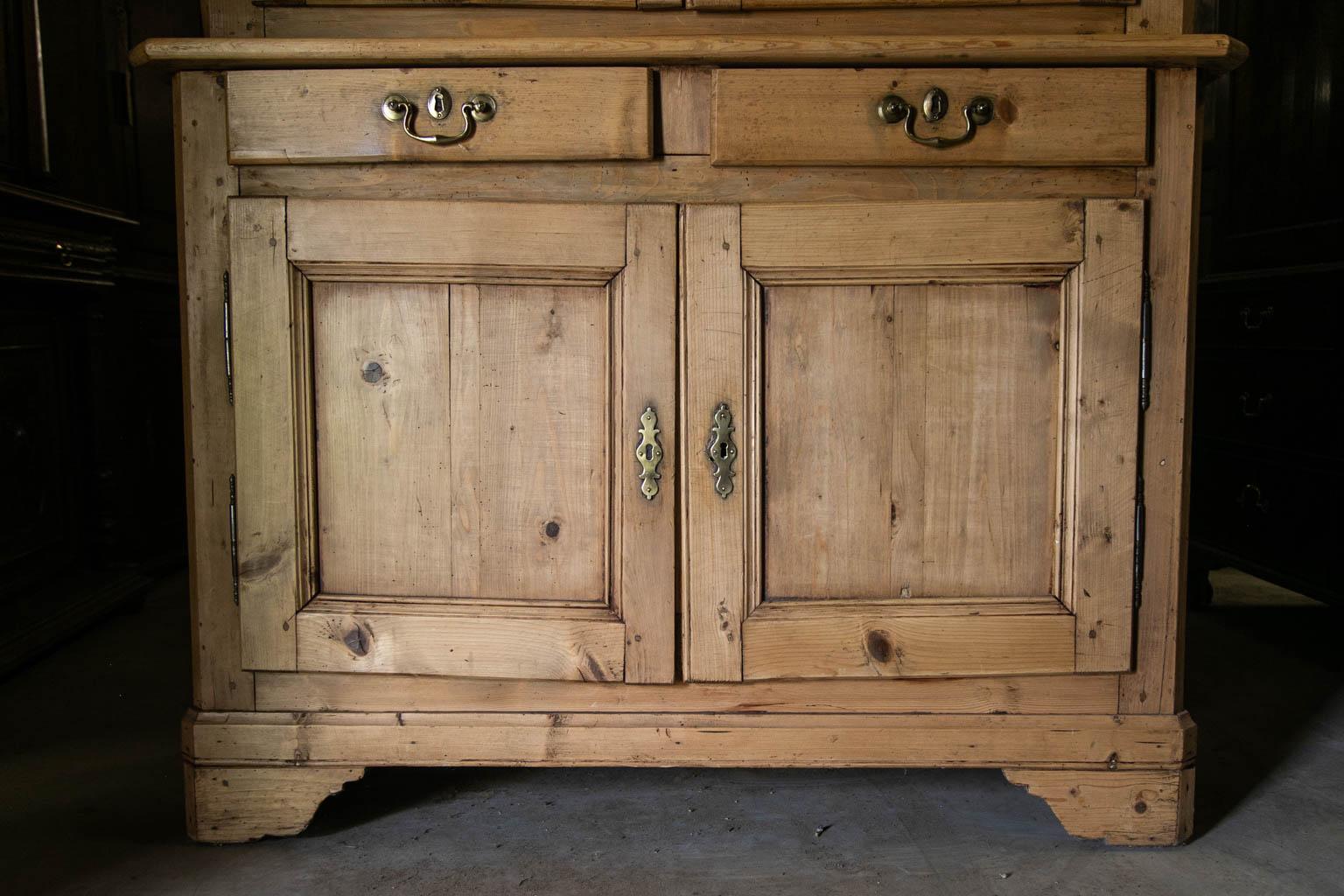 This cupboard has exposed peg construction. The sides have recessed panels on the top and bottom. The doors have recessed panels framed with carved molding. The interior of the upper half has two fixed shelves while the lower half has one. The sides