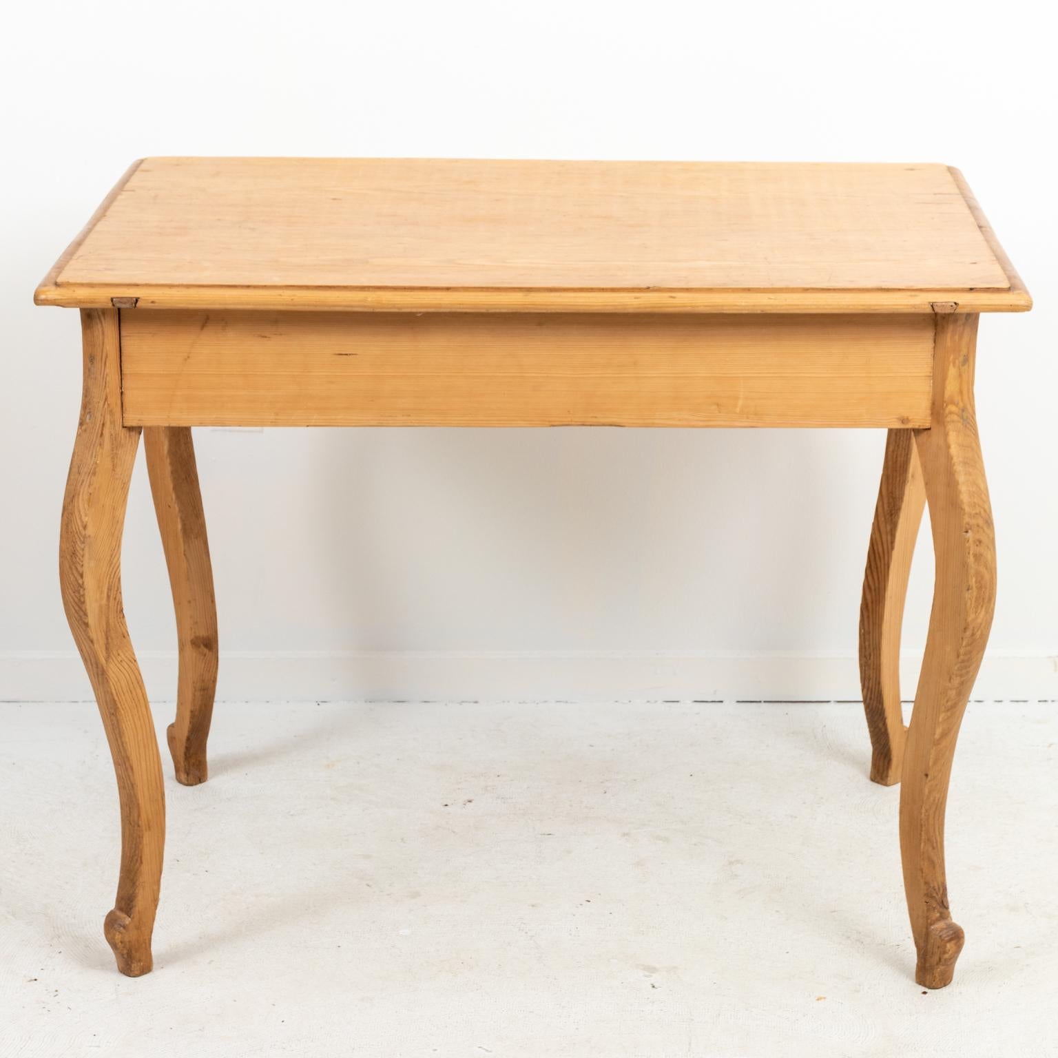 French pinewood table with one drawer and cabriole style legs, circa 1880s. Made in France. Please note of wear consistent with age including minor fading, finish loss, wood loss, and chips. There is also a large crack on the tabletop.