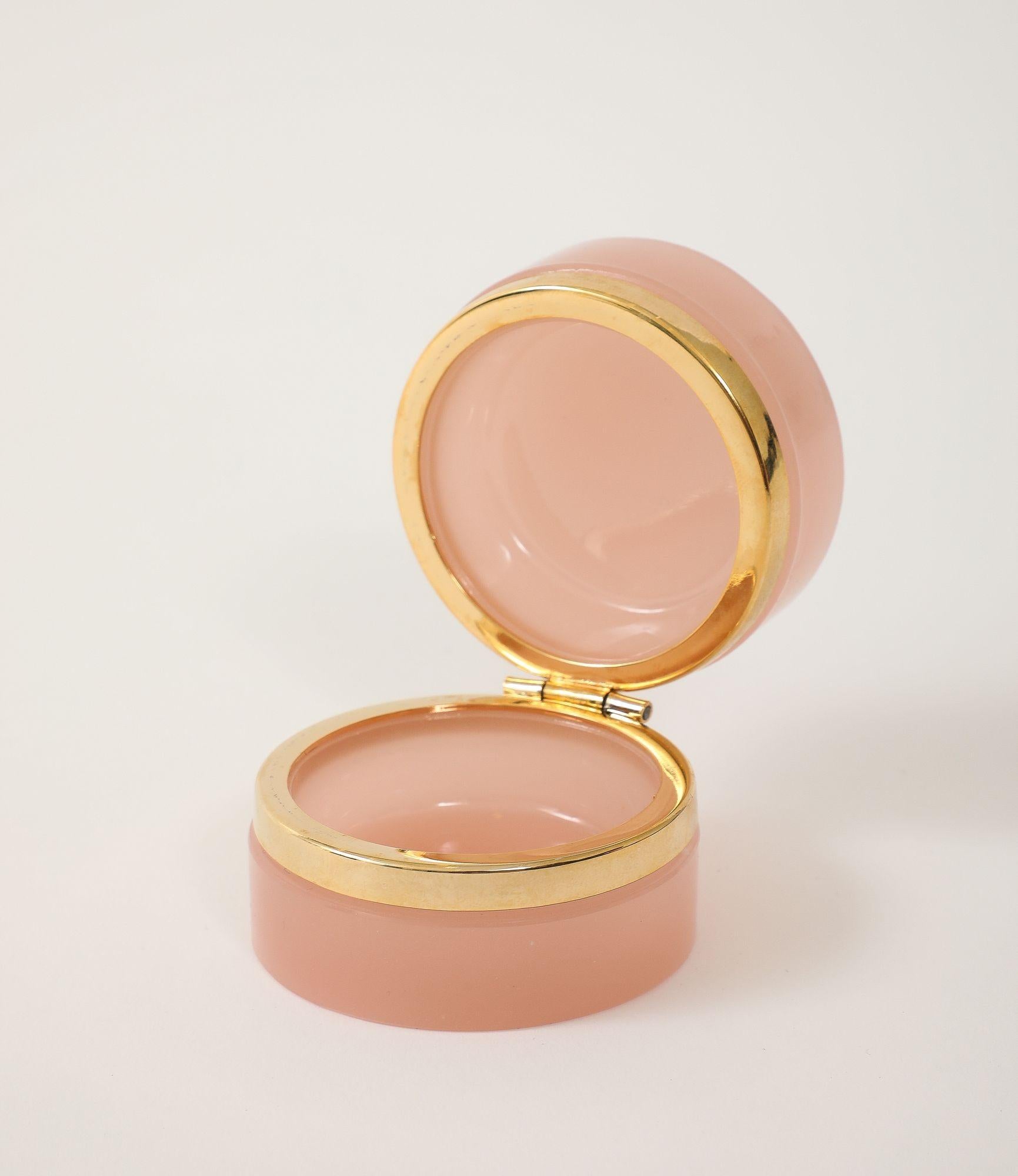 Una rara mini scatola rotonda in vetro opalino di colore rosa pallido, risalente agli inizi del XX secolo in Francia. Questo pezzo di grande effetto è caratterizzato da montature originali in ottone e da un coperchio con cerniera, che ne evidenziano