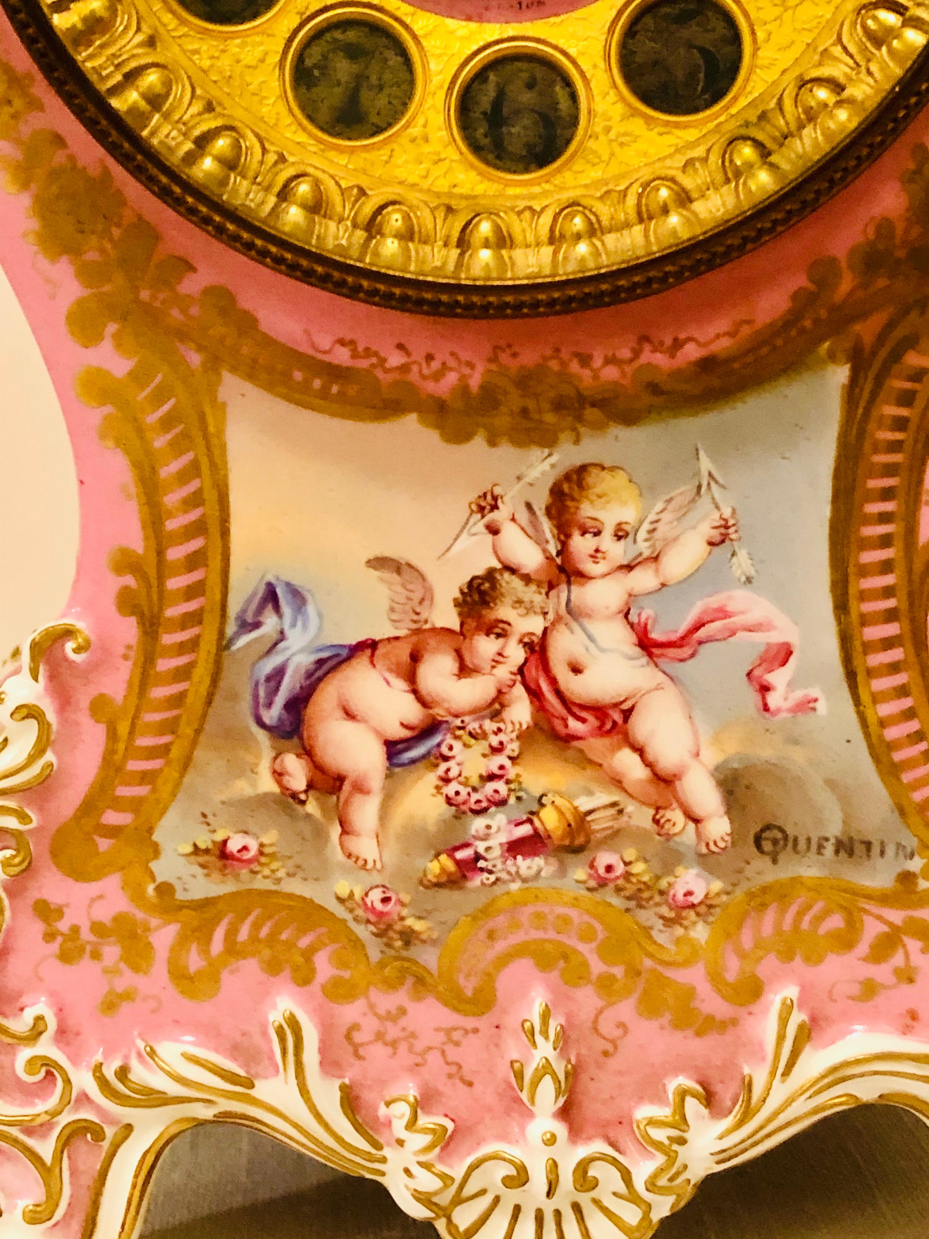 I am proud to offer you this magnificent porcelain Longwy French clock, which is painted with cherubs and artist signed Quentin. The pink pompadeur color of this fabulous mantle clock is eye-catching. The beautiful paintings of the cherubs with