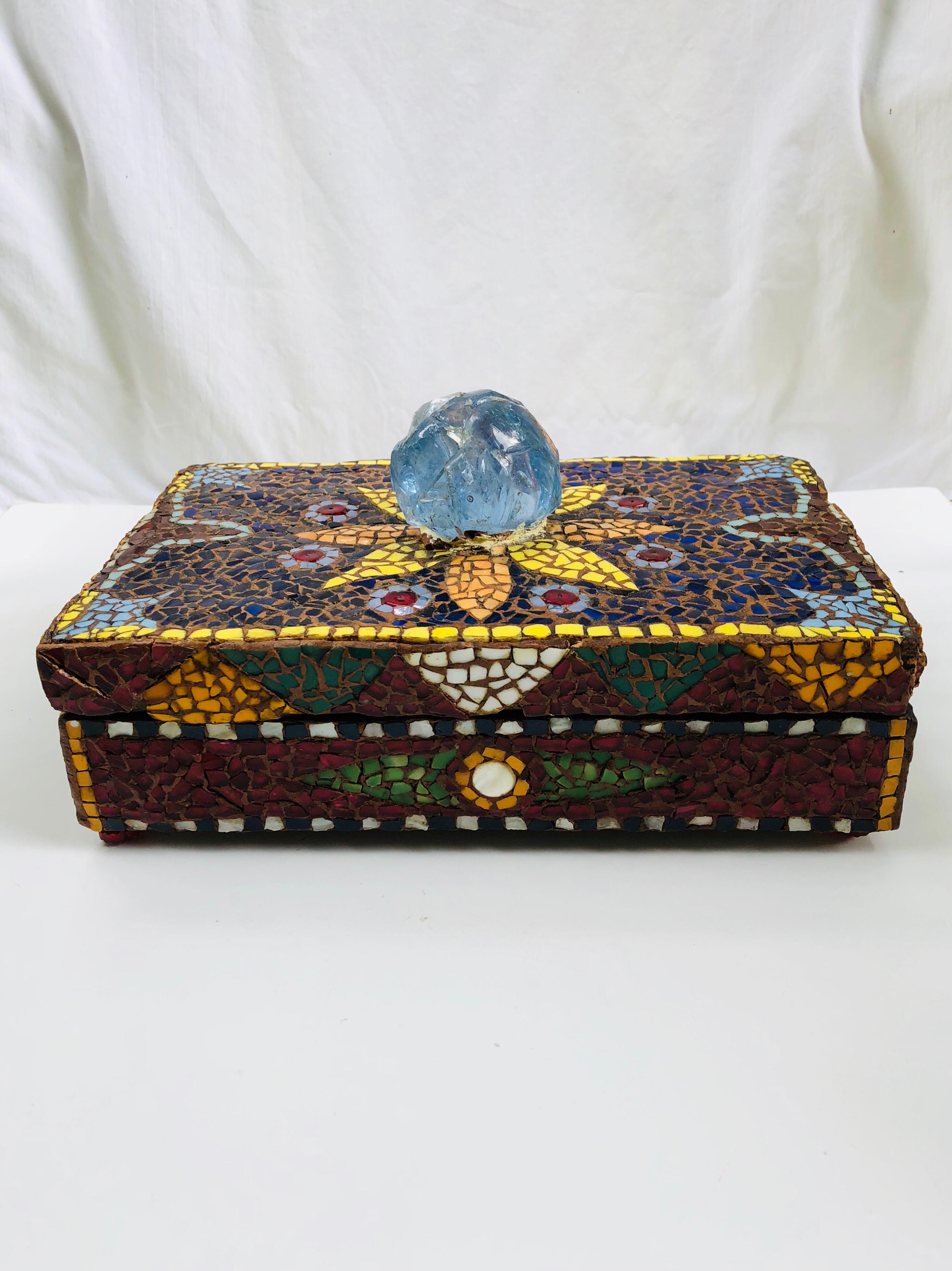Pique Assiette French mosaic rectangular box with an enormous piece of blue translucent glass on the lid. Starburst pattern on the lid. Decorated with porcelain fragments on the entire surface, circa 1950. Red carved glass beads support the