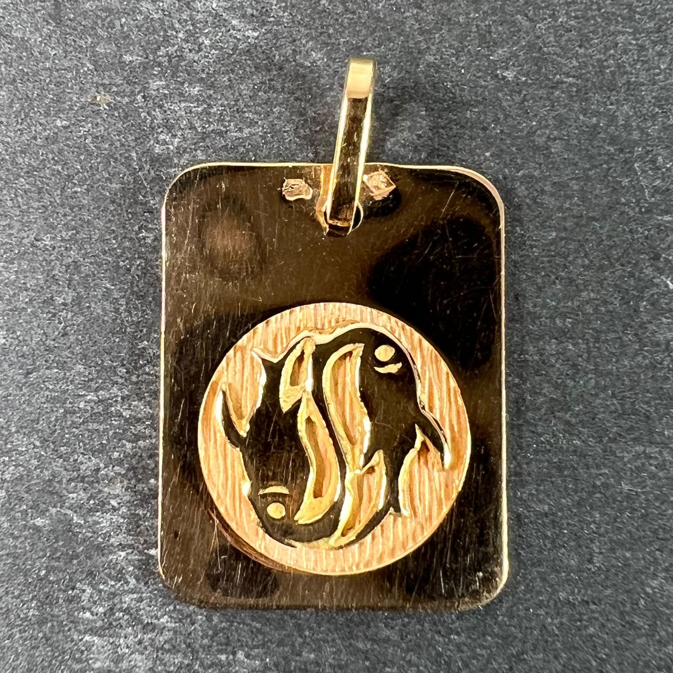 Colgante francés de oro amarillo de 18 quilates (18K) diseñado como una medalla rectangular con un hueco circular grabado que representa una pareja de peces del signo zodiacal de Piscis. Estampado con la cabeza de águila de fabricación francesa y
