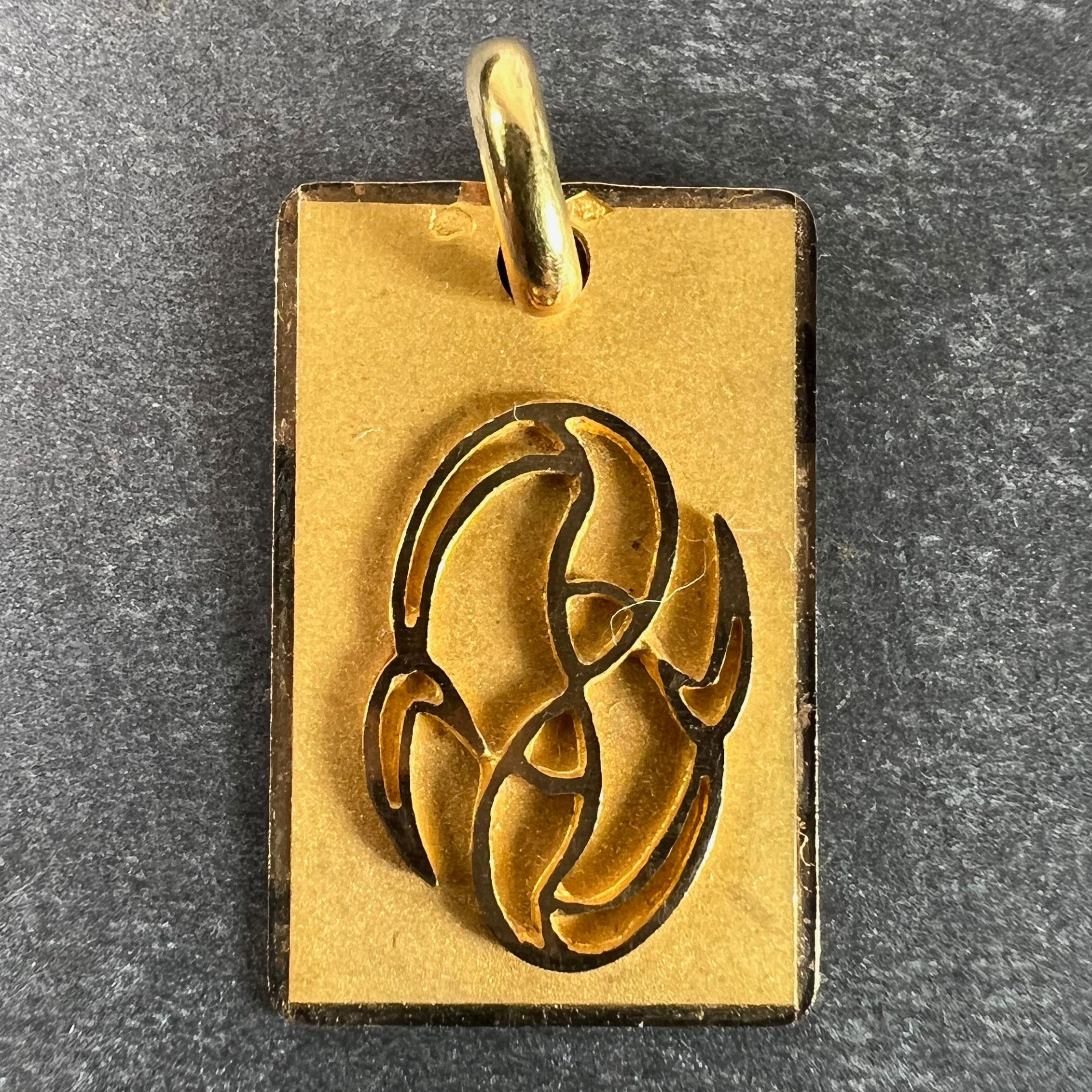 A French 18 karat (18K) yellow gold charm pendant designed as a rectangular medal with a matt surface and polished lines in relief depicting a pair of fish representing the zodiac star sign of Pisces. Stamped with the eagle’s head for French