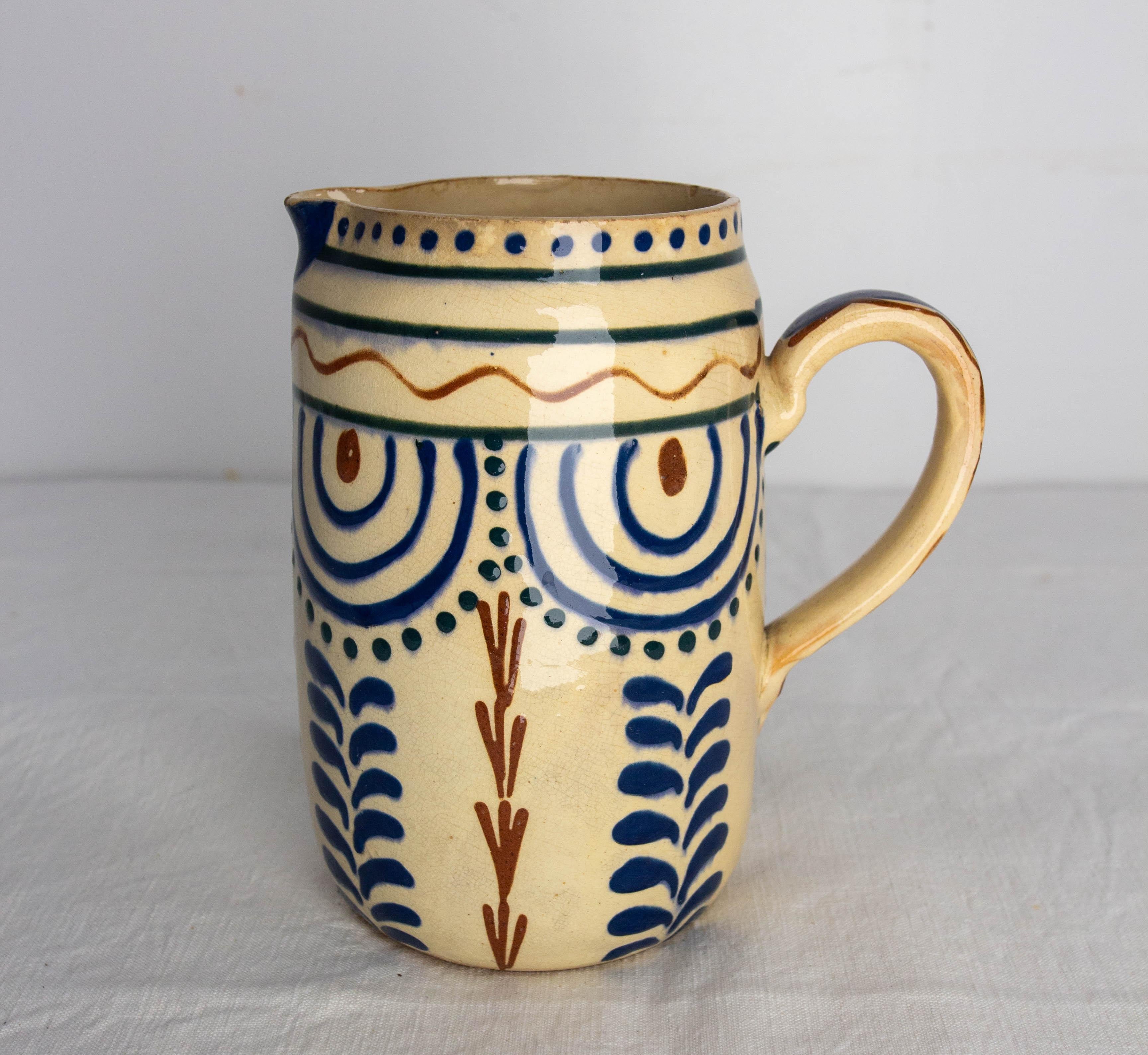 French pitcher in glezed 
Red and blue patterns, numbered
This picher can also be used as a vase
Small chip due to use on the moldboard, non-structural

Shipping: 
L 17 P 12 H 18 0.8 Kg.
