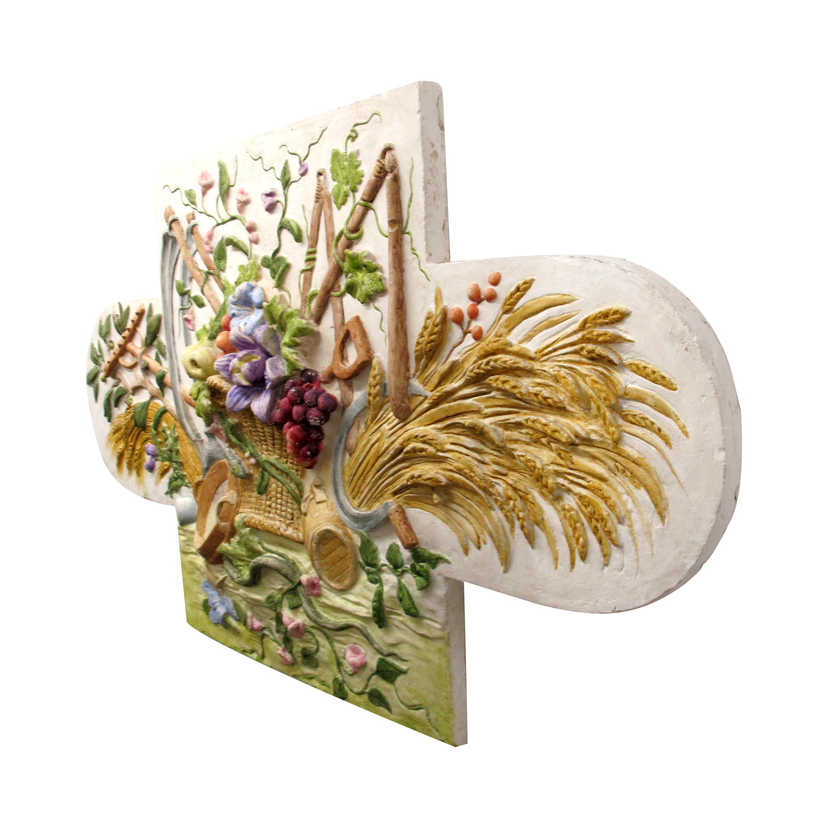 Fronton en plâtre vintage fait à la main, représentant une scène de moisson détaillée avec du blé, des fleurs, des fruits et des outils traditionnels. Elle est peinte à la main dans des tons chauds et naturels. Parfaite au-dessus des portes, des