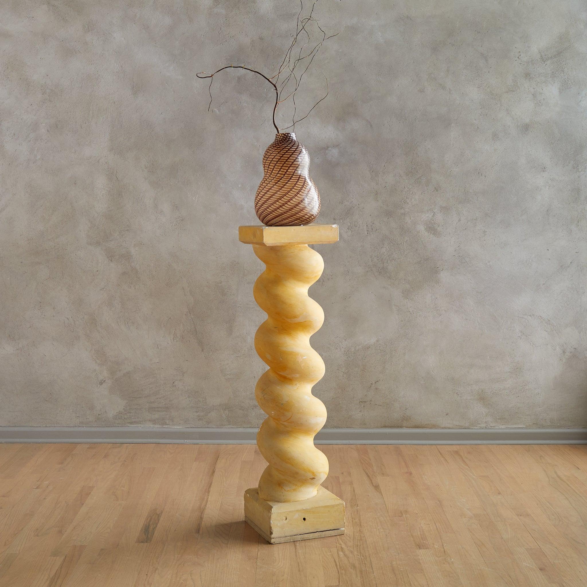 Ce piédestal français des années 1980 présente une silhouette ludique en spirale réalisée en plâtre et posée sur une solide base en bois. Sa forme totémique et sa finition ocre douce lui confèrent un intérêt architectural - idéal pour exposer des