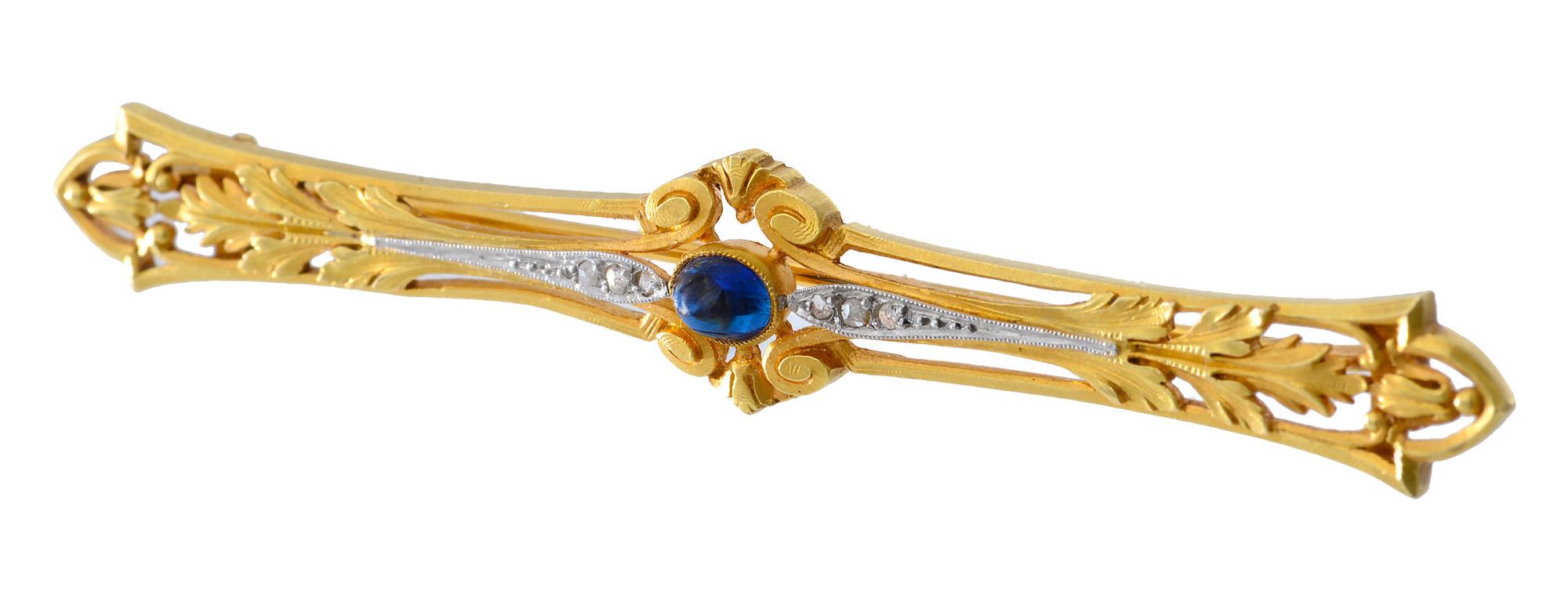 A crisp and beautifully made French gold brooch set to the centre with a pretty cabochon sapphire with three platinum set diamonds to either side. The terminals of the brooch are adorned with foliate design gold work. It is 1.2 cm at its widest