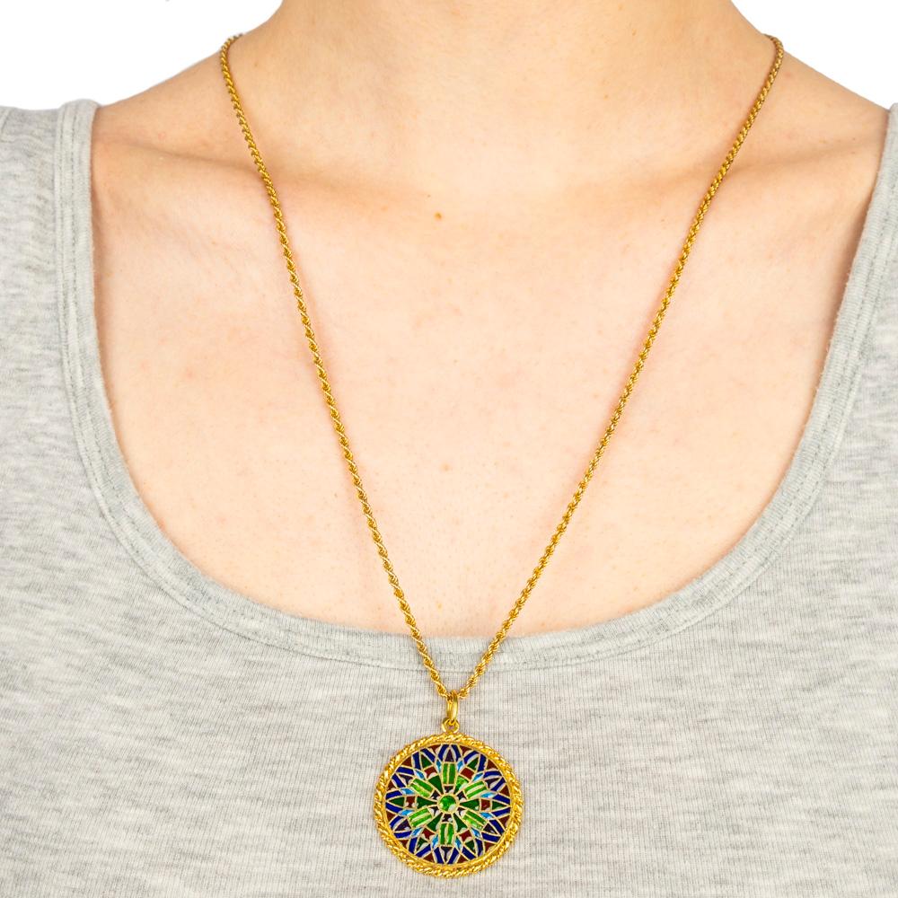 Recalling the stain glass windows of Notre Dame Cathedral in Paris, this 18k gold pendant is decorated with plique a jour (transparent) enamel of vibrant colors, separated by gold cloisons with a gold ropetwist border. Chain not included. 

French,