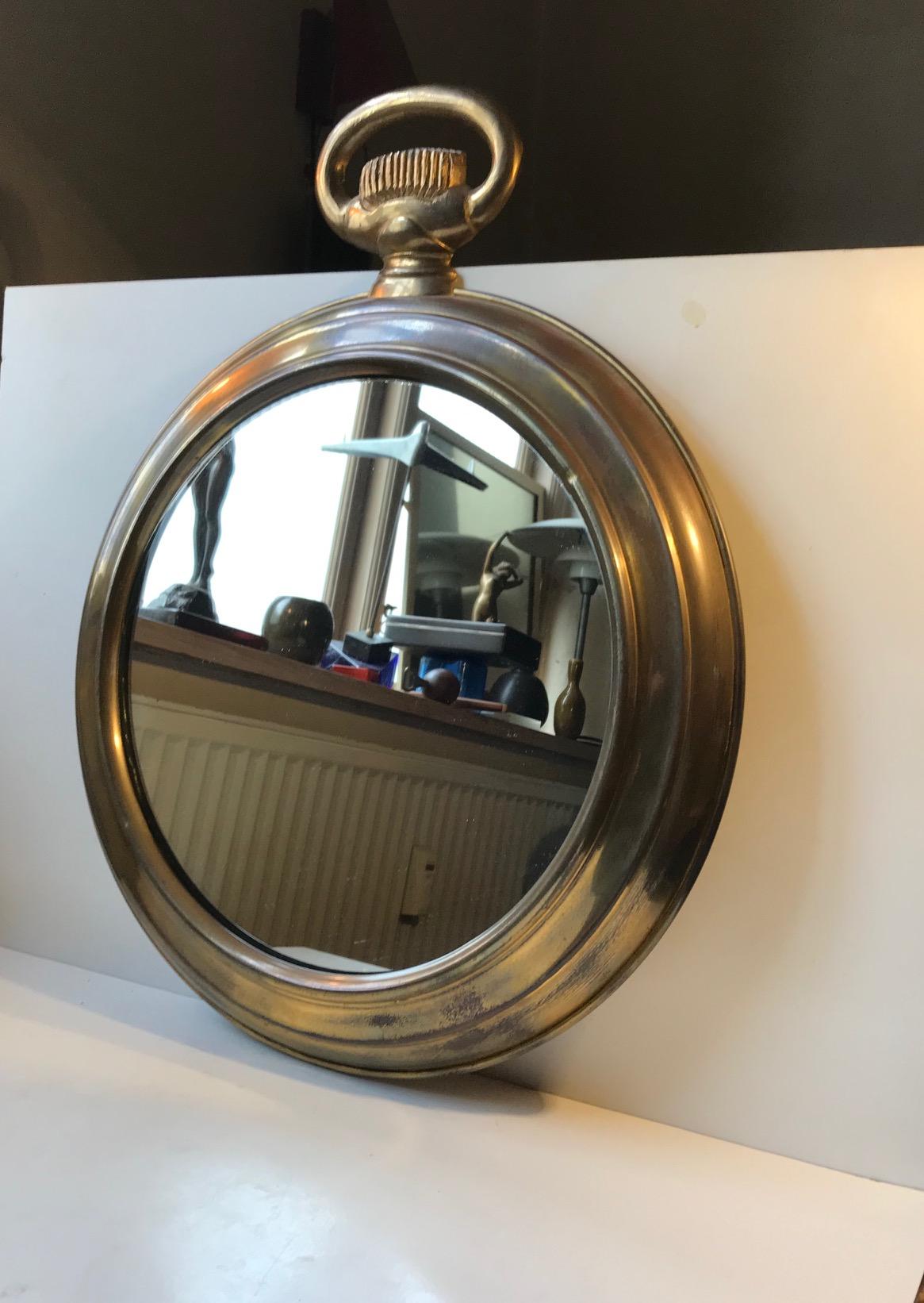 A round brass pocket watch mirror made in France during the 1950s. Its frame is made from solid brass that has developed a Natural patina. Its suitable for bathrooms, small alcoves or in your entrance reception area. Dimensions: 49 W x 63 H x 6.5 D