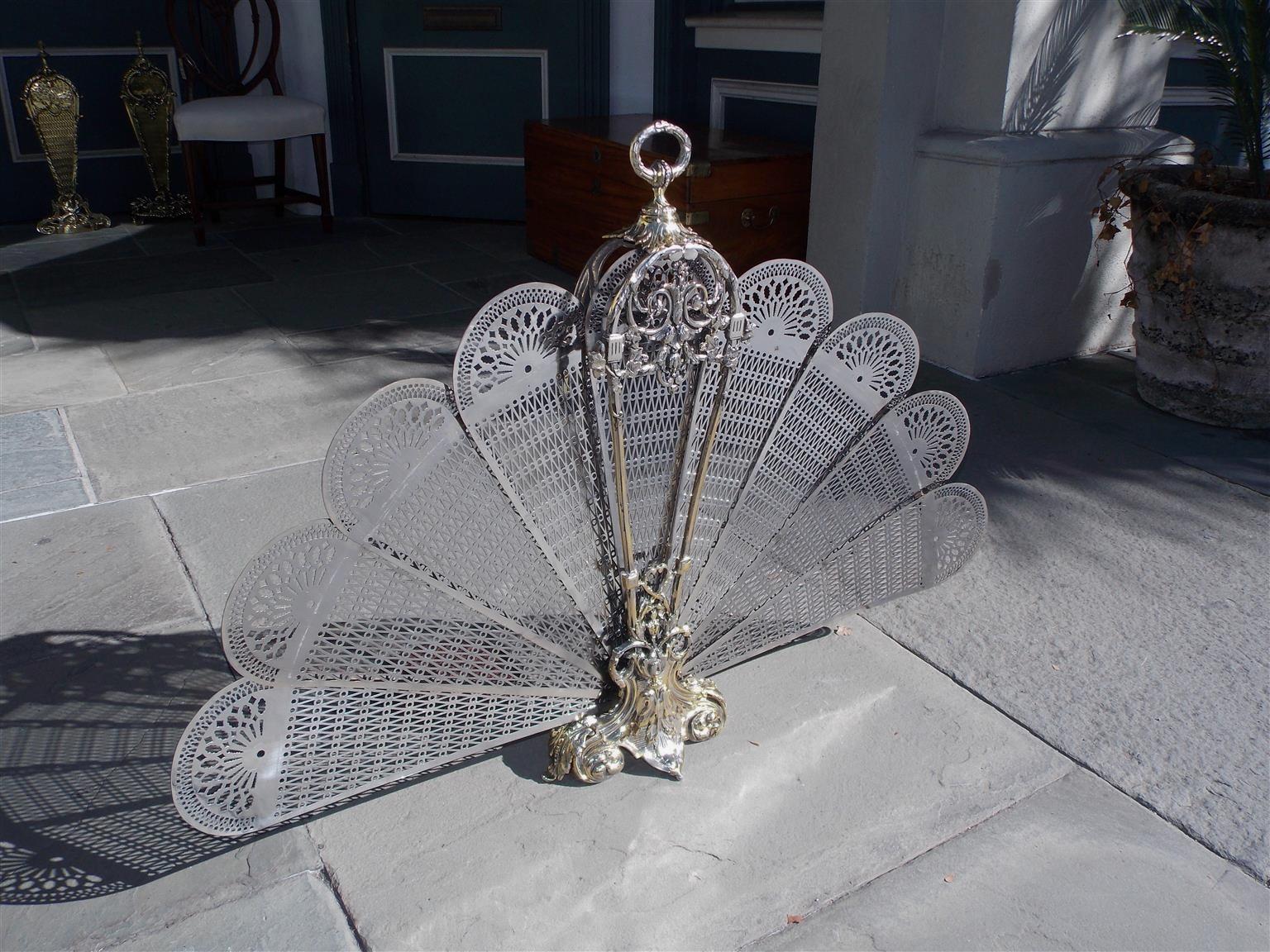 French polished steel fire place screen with centered ribbon handle, decorative pierced chased folding fans, bell flower motif, and terminating on a scrolled acanthus base with flanking floral medallions, Early 19th century.