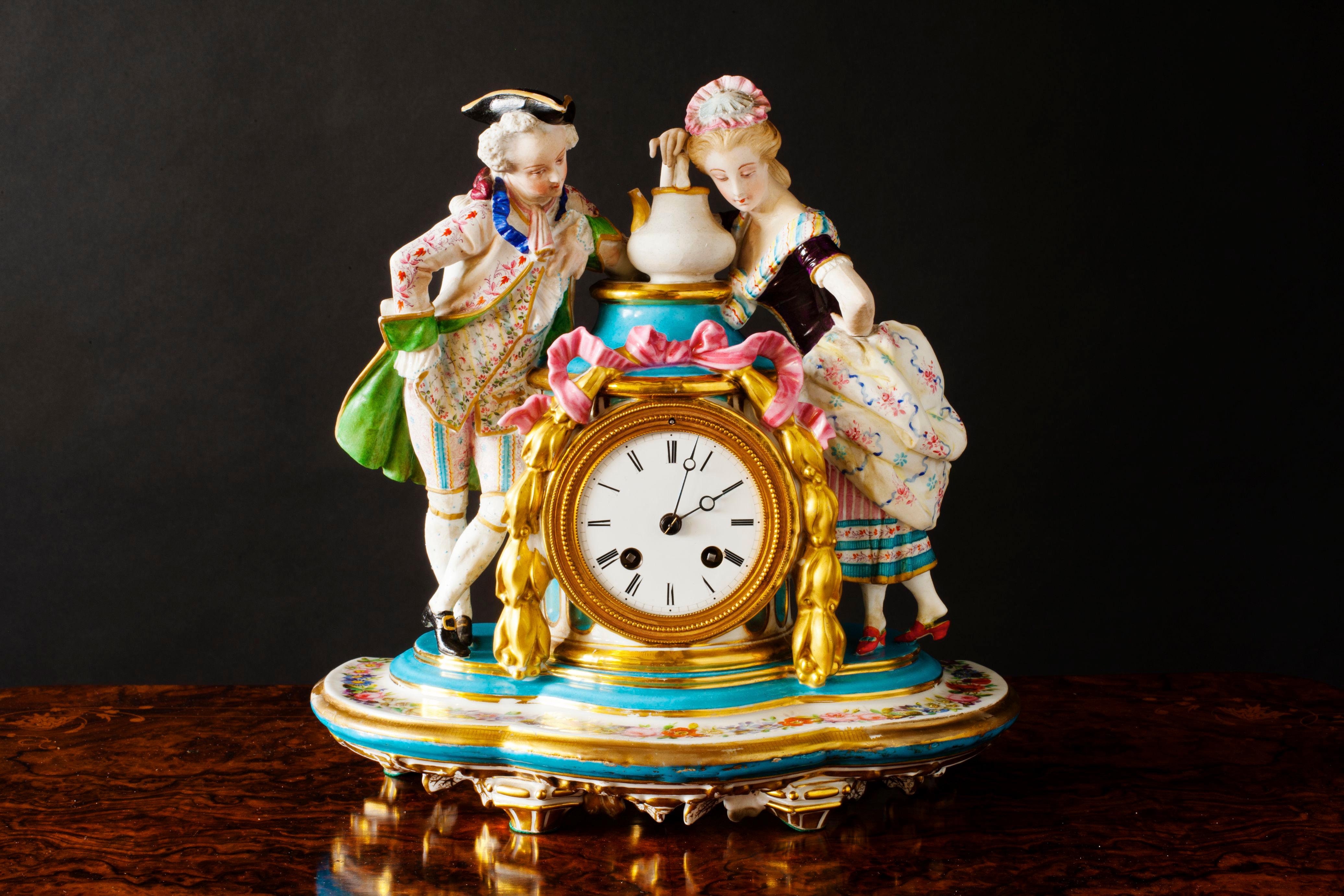 French Porcelain and Bisque pottery mantel clock with floral decoration and gilded garlands supporting a French Nobleman and his mistress. Beautifully decorated with an enamel dial and Roman numerals to the French eight day movement with outside