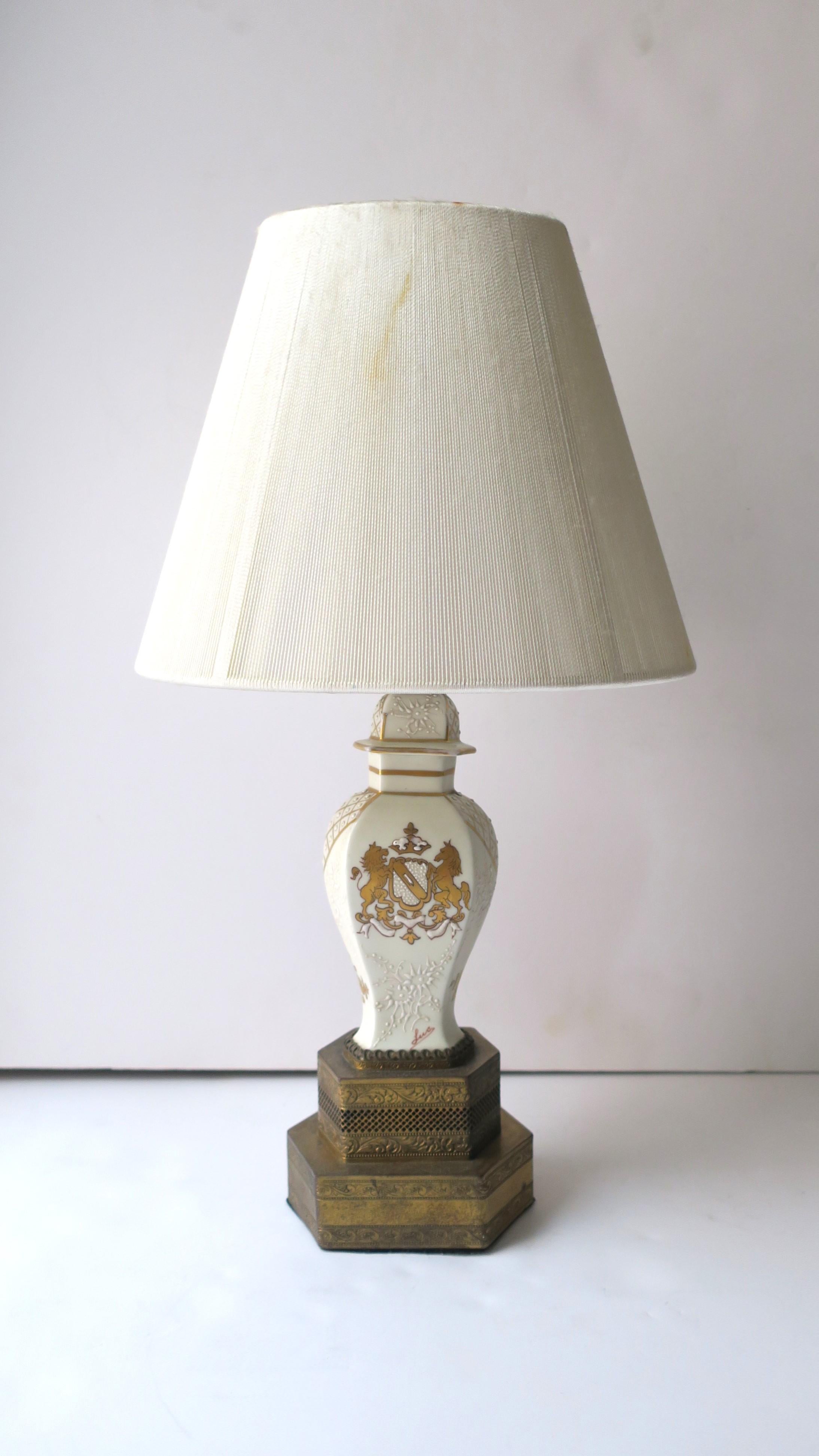 A small French porcelain table lamp with brass base, in the Empire style, circa early-20th century, France. This small French porcelain lamp, with graduated brass 'hexagon' base, has a white raised relief on front, sides, and back. Front center