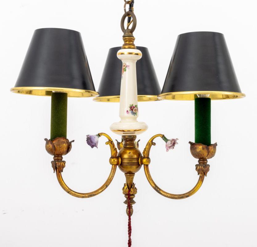 Lampadario francese a tre luci in porcellana dipinta e ottone, con bracci a bocciolo di rosa e paralumi neri in metallo patinato con nappe in tessuto rosso. 31