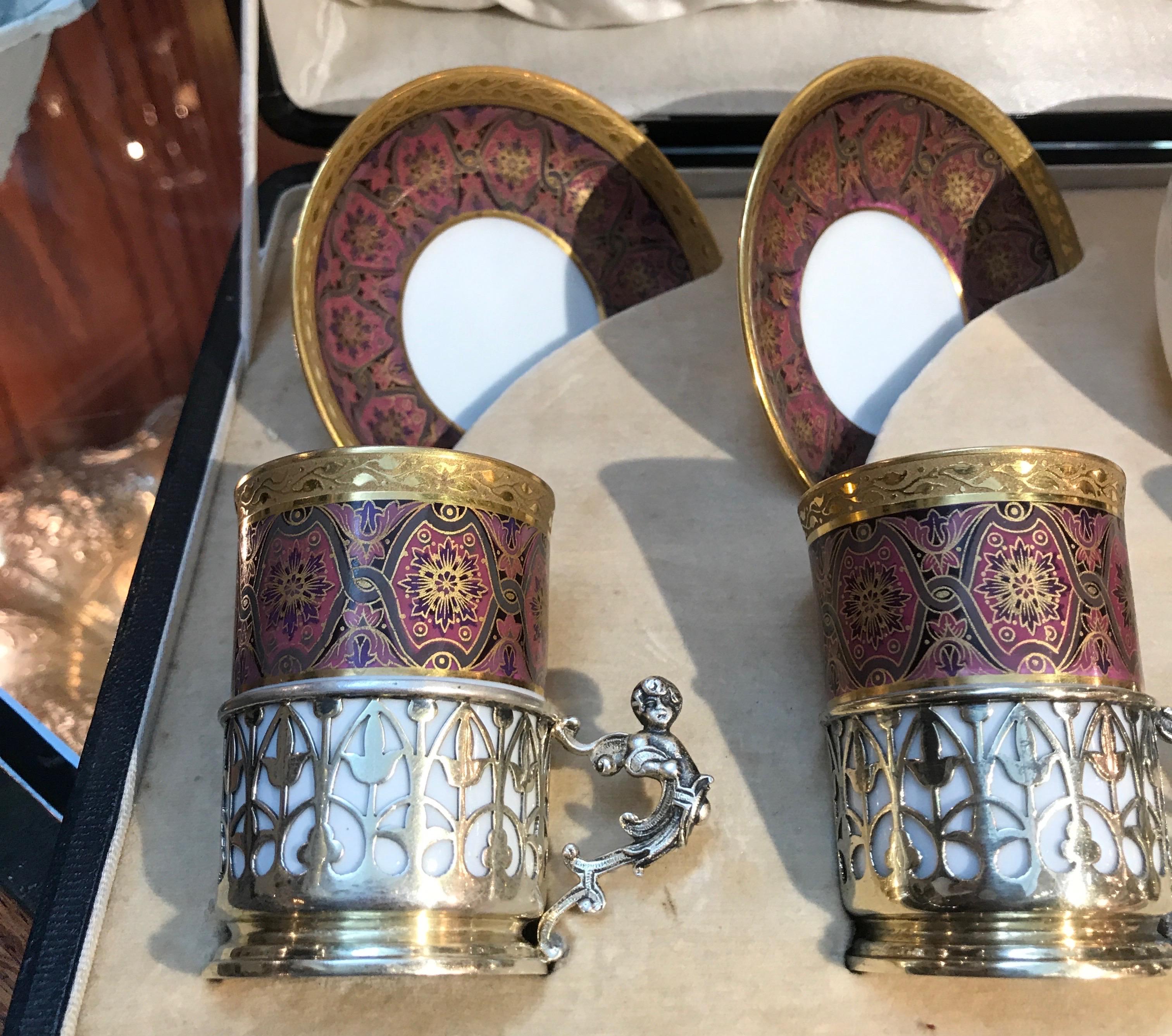 Elegant set of 4 Limoges French porcelain demitasse cups and saucers. The set with English Birmingham sterling silver holders in original presentation box. The set is decorated in a Persian design with gilt trim. The black leather covered box with