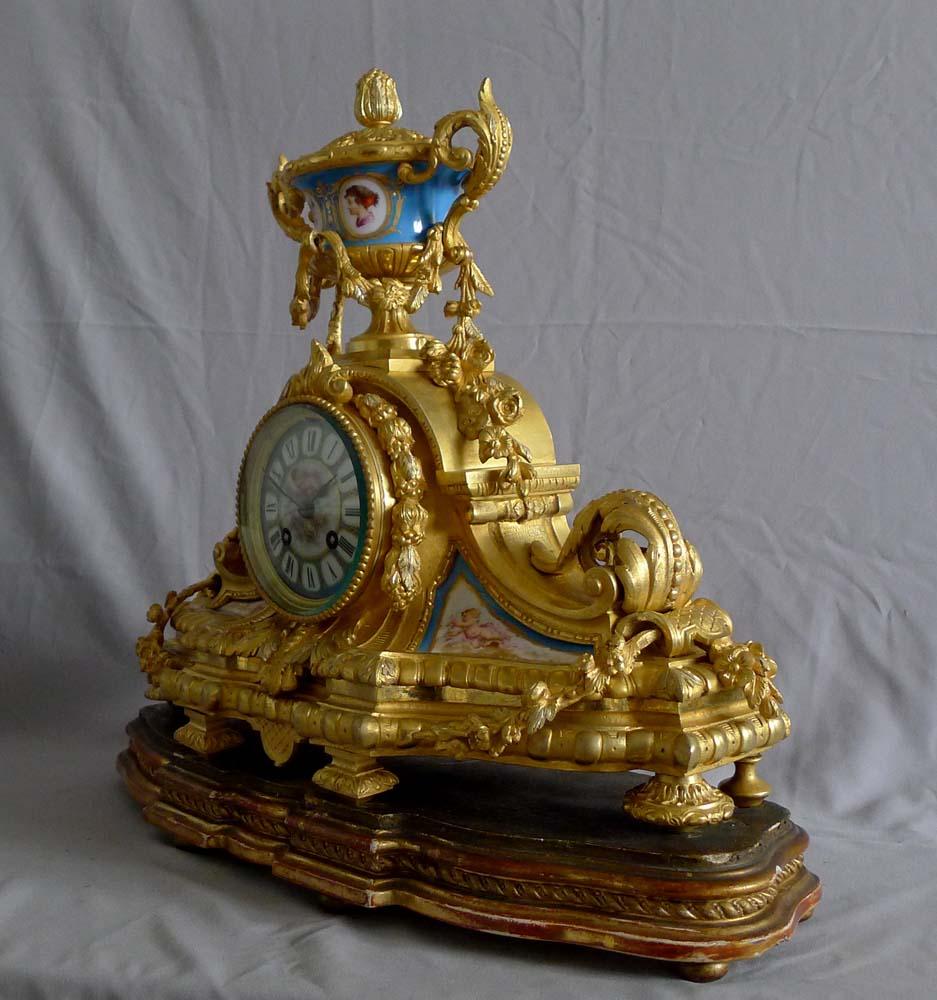 Pendule de cheminée en porcelaine française et bronze doré avec des reflets argentés. Une superbe horloge Napoléon III dans le style Louis XVI. L'ormolu doré au feu/mercure d'origine est en très bon état mais présente également de magnifiques
