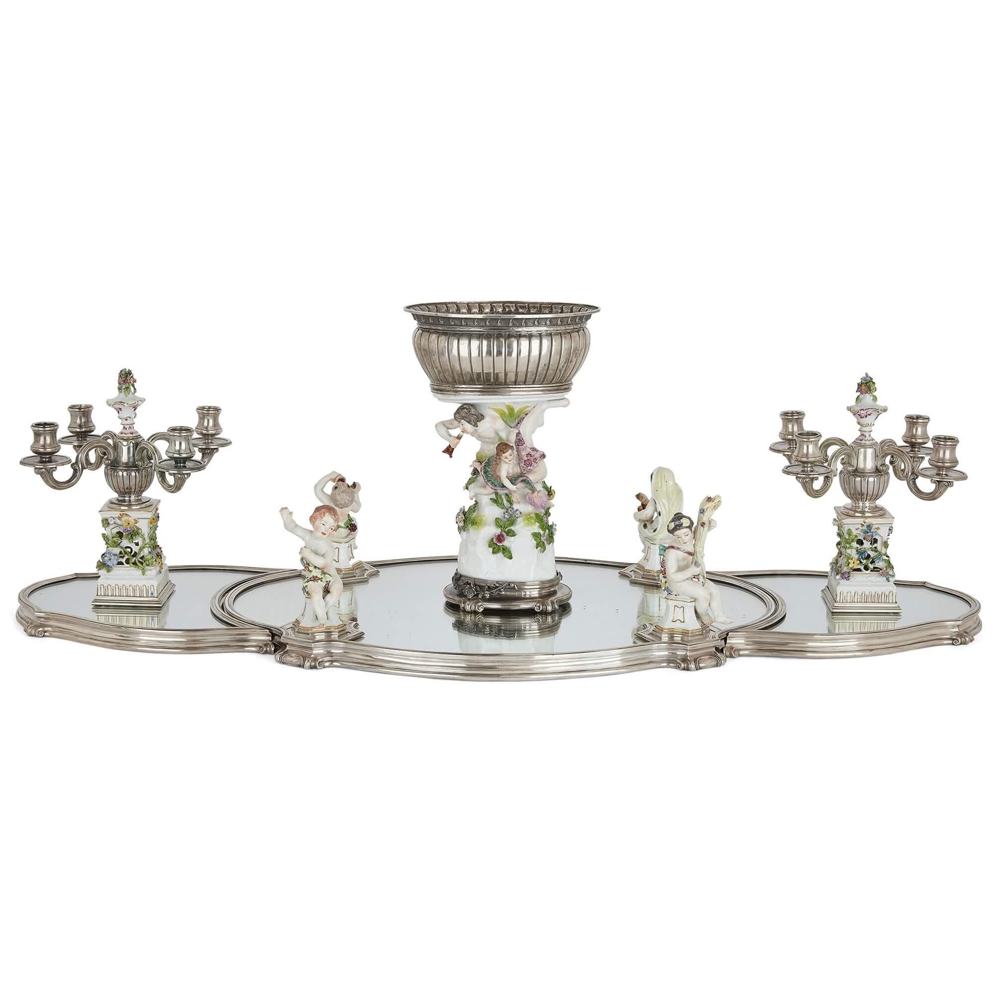 French porcelain and silver centrepiece suite by Tétard and Samson
French, early 20th Century
Tray: Height 3.5cm, width 117cm, depth 43cm
Central comport: Height 35.5cm, width 23cm, depth 17cm

This very fine centrepiece surtout is crafted from