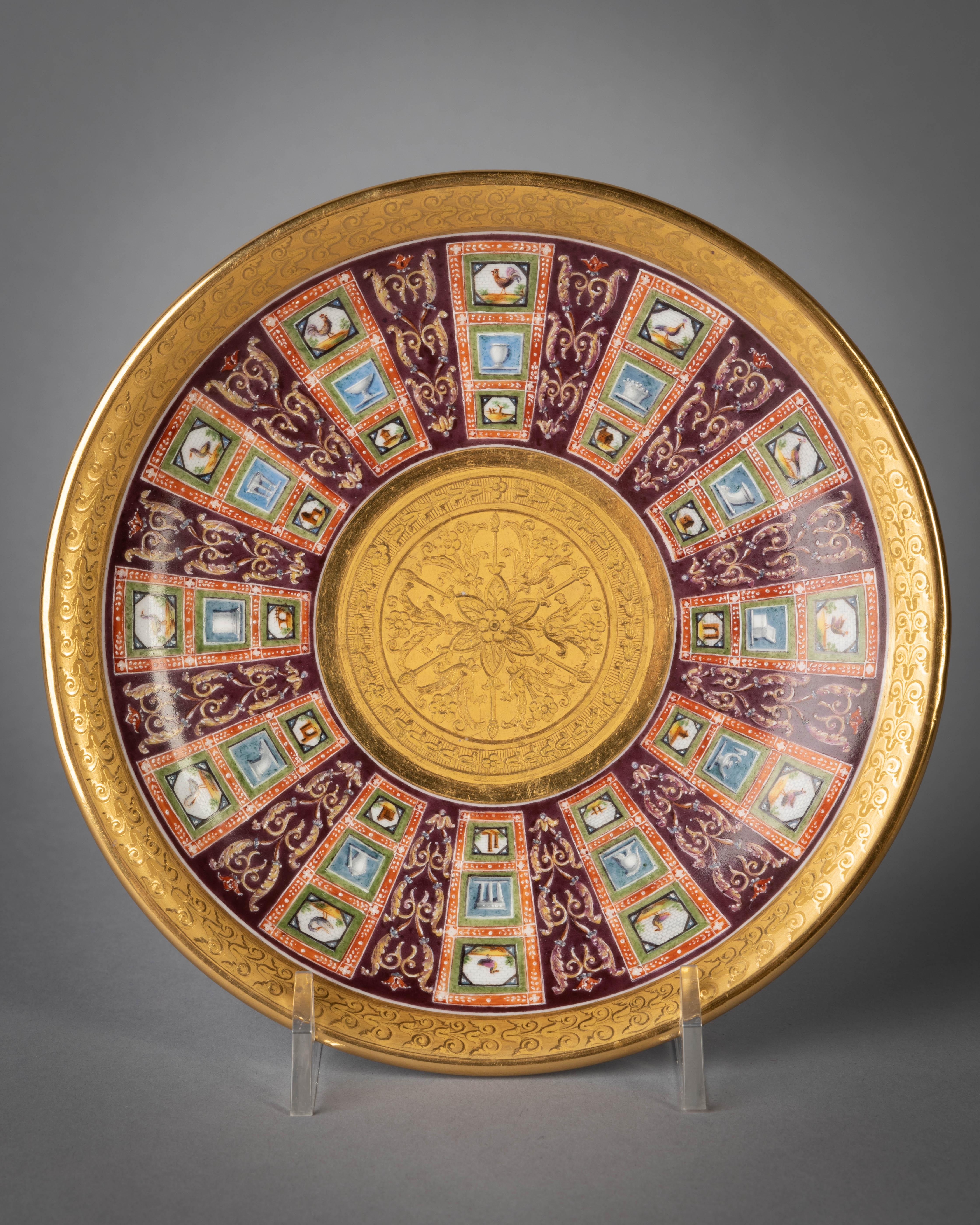 The cup with elaborate gilt scroll handle terminating in a palmette, the sides finely painted in colors with graduated octagonal cartouches enclosing birds and ruins, painted to resemble micro-mosaics alternating with blue faux marble panels painted