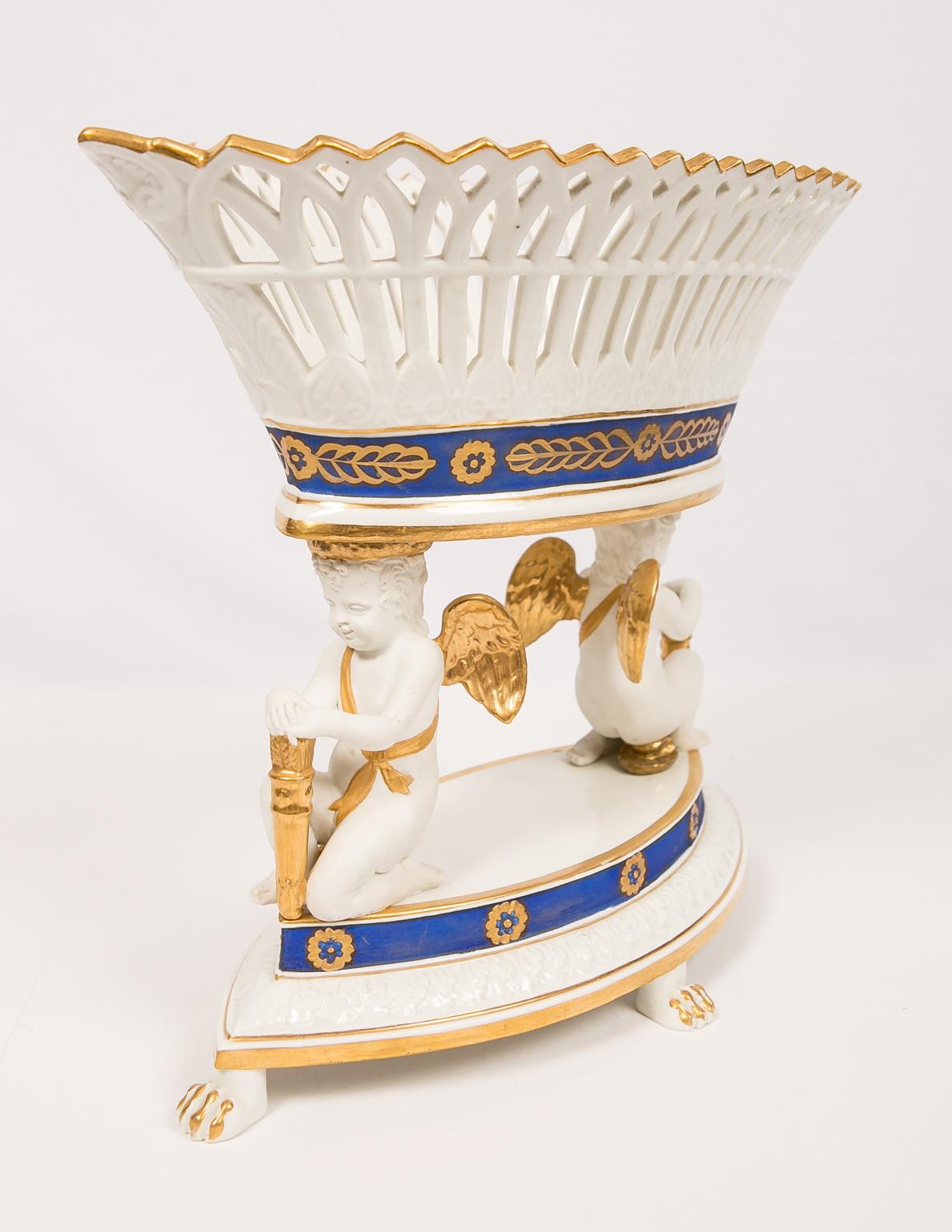 We are pleased to offer this large French porcelain centerpiece with angels supporting a pierced basket. The pierced basket is oval shaped. The porcelain angels are made in the bisque, seated on a oval base. The fine white of the porcelain is