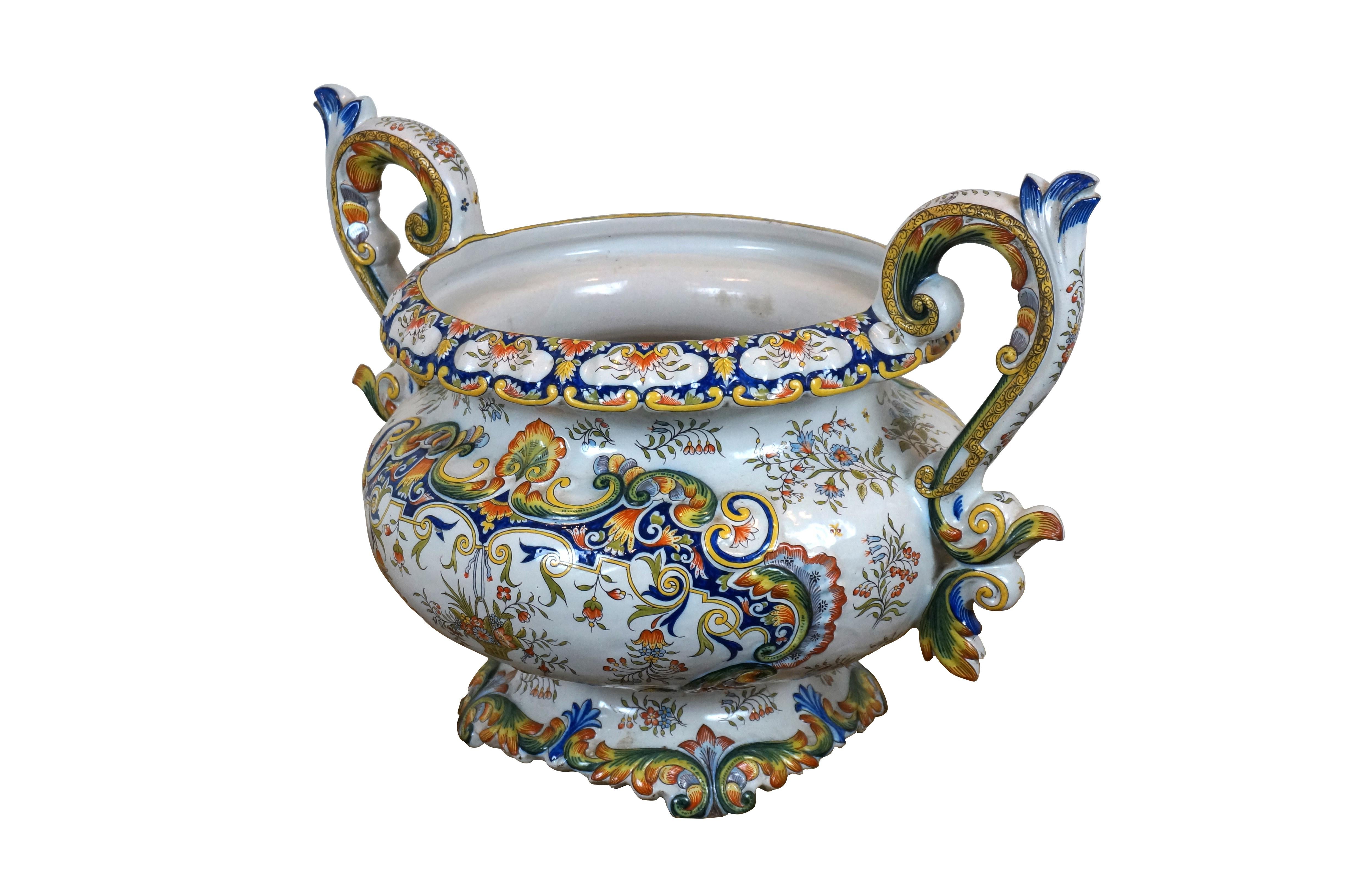 Urna / jardiniere / fioriera / cachepot in porcellana francese smaltata di maiolica con un ornato disegno floreale e fogliare in blu, giallo e arancione su fondo bianco. Forma ovale affusolata con base e bordo smerlati e due manici a volute