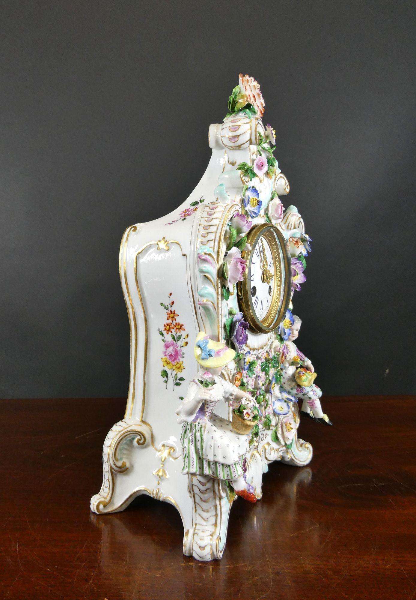 Französische Porzellan Figurale Kaminsimsuhr
Französische figurale Kaminuhr aus Porzellan, schön verziert mit Blumen auf weißem Grund, mit Gitterwerk in der Mitte und auf ausladenden Füßen stehend. Die Uhr wird von einer Dame und einem Herrn auf