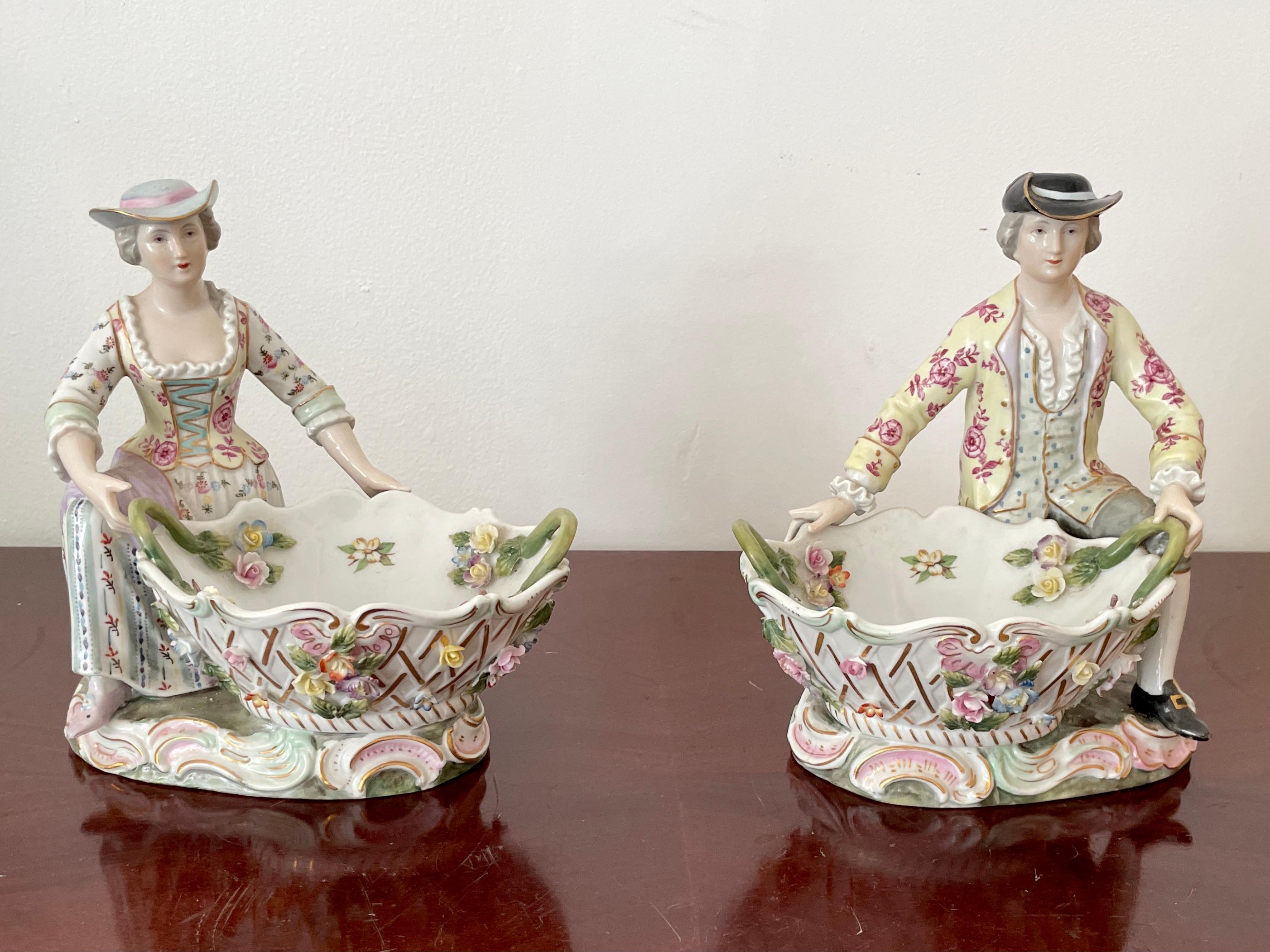 Pair of beautiful French porcelain figurines of a man and a woman holding large baskets with amazing details. These are not only for decoration but also work great as bowls. Great addition to your classic inspired table tops and interiors.