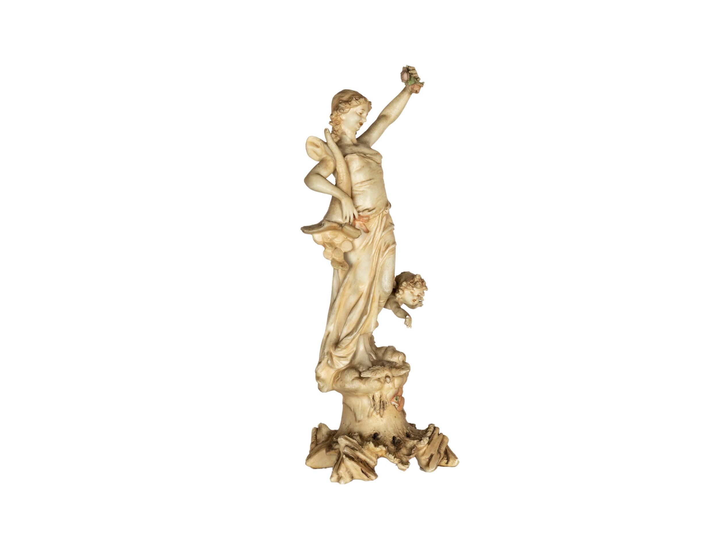 An Art Nouveau stunning French porcelain statue of the goddess of Fortune, Tyche, depicting the goddess holding a cornucopia overflowing with gold coins, surrounded by a cherubim and a peaceful dove, a symbol of good fortune and prosperity.
